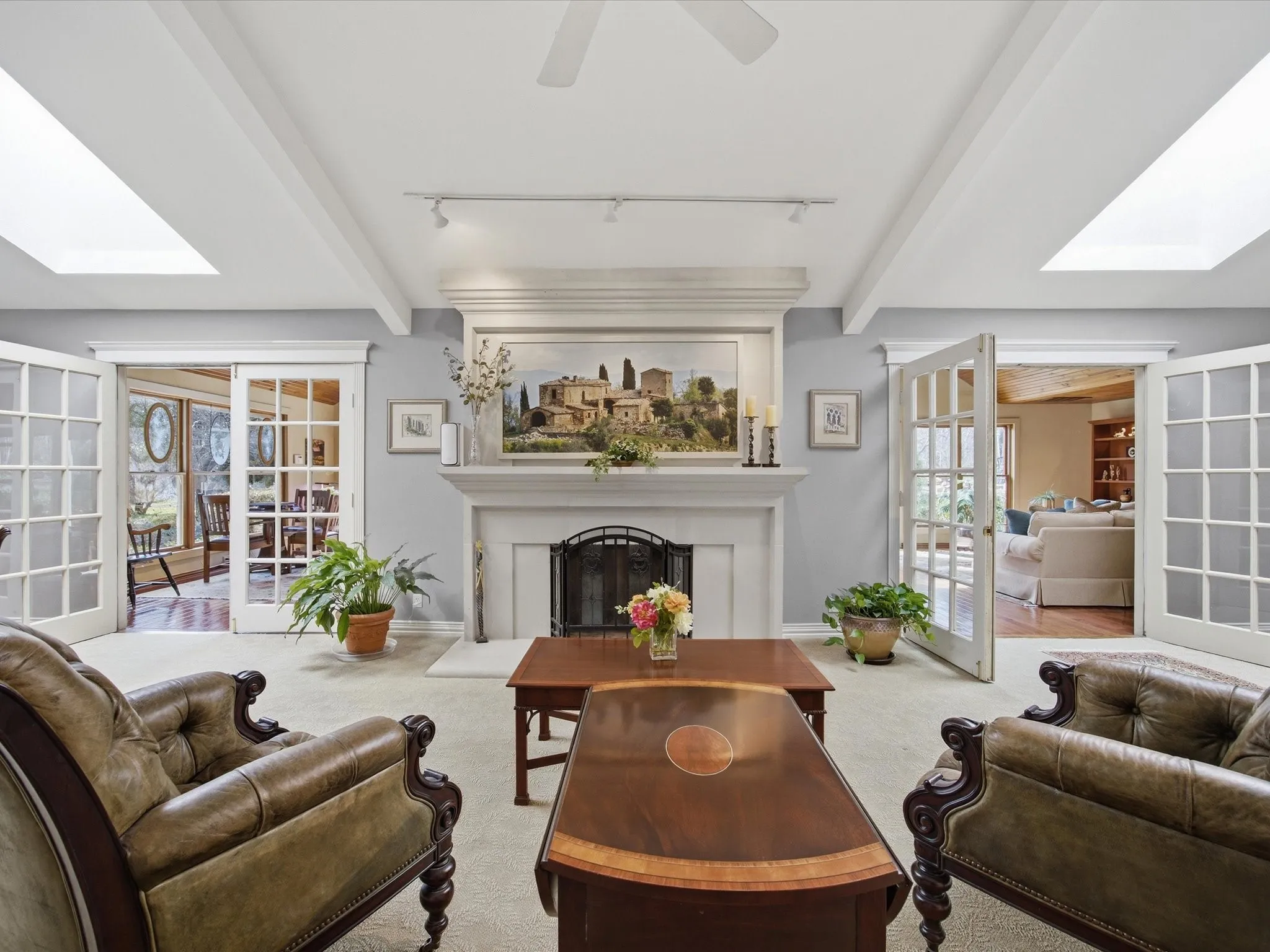 Living room featuring french doors, beamed ceiling, carpet flooring, a fireplace, and track lighting