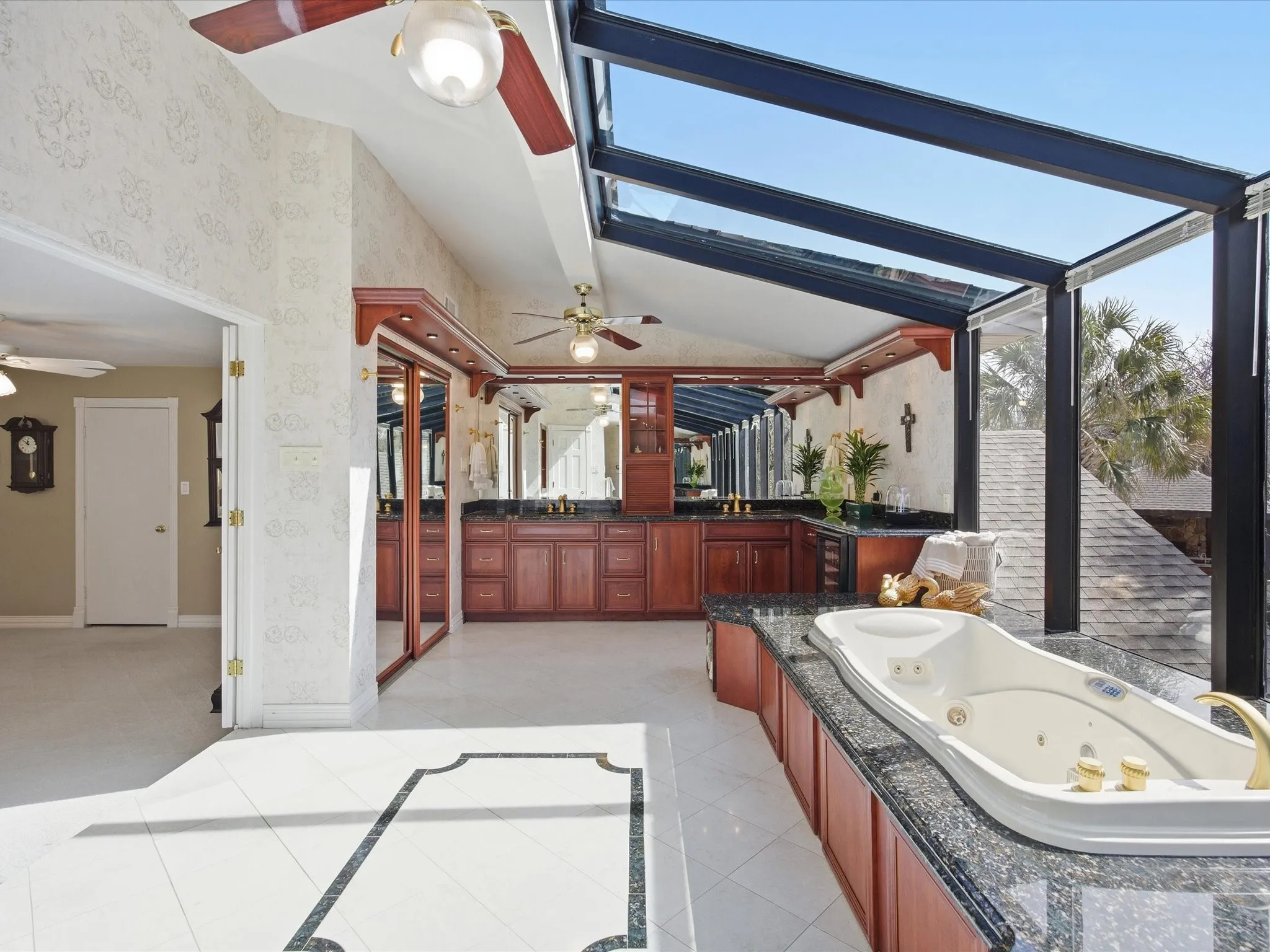 Upstairs Primary Bathroom featuring vanity, light tile patterned floors, wallpapered walls, a tub with jets, and ceiling fan