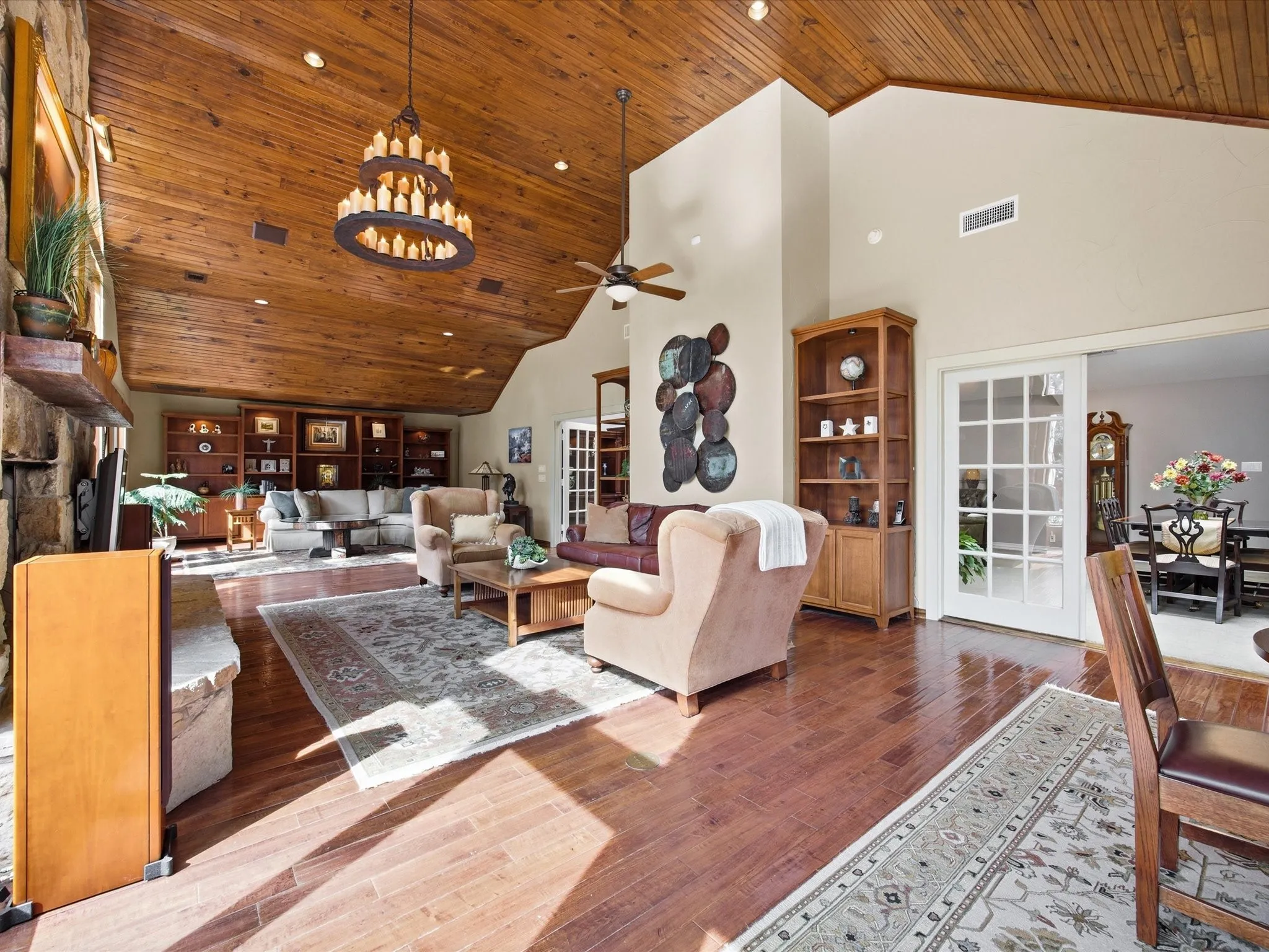 Living room with a vaulted wood ceiling, wood-type flooring, a fireplace, ceiling fan, and suspended lighting