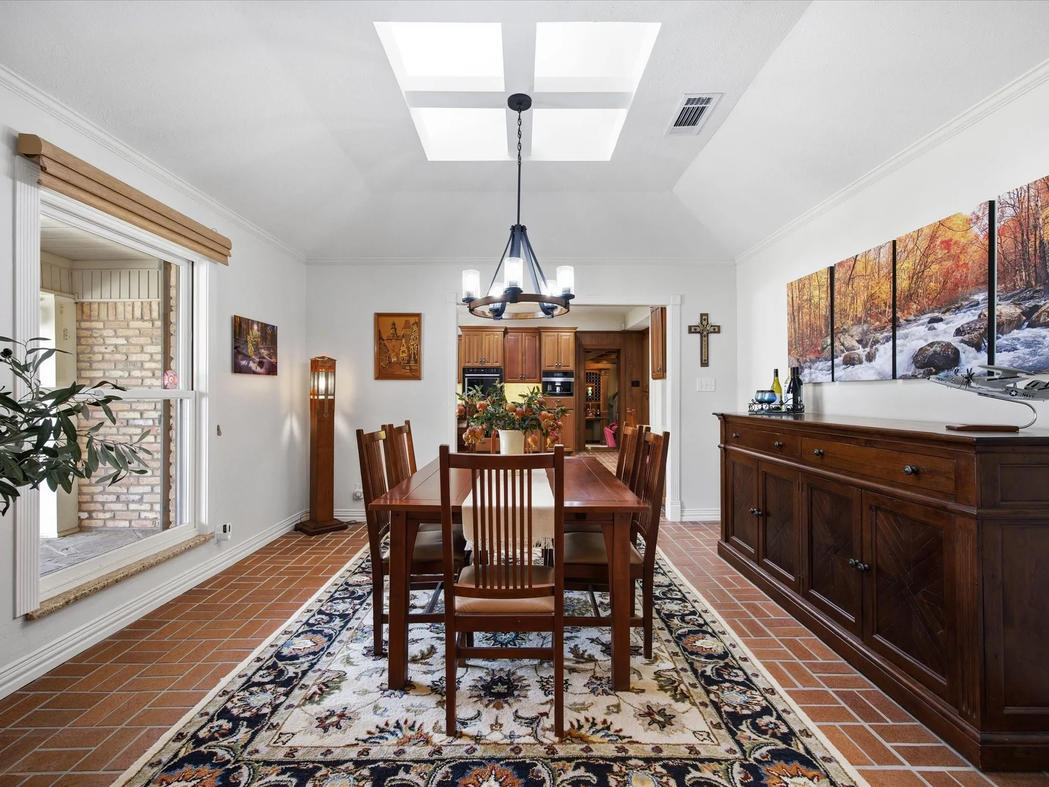 Dining area with brick patterned flooring, a skylight, crown molding, and hanging lights