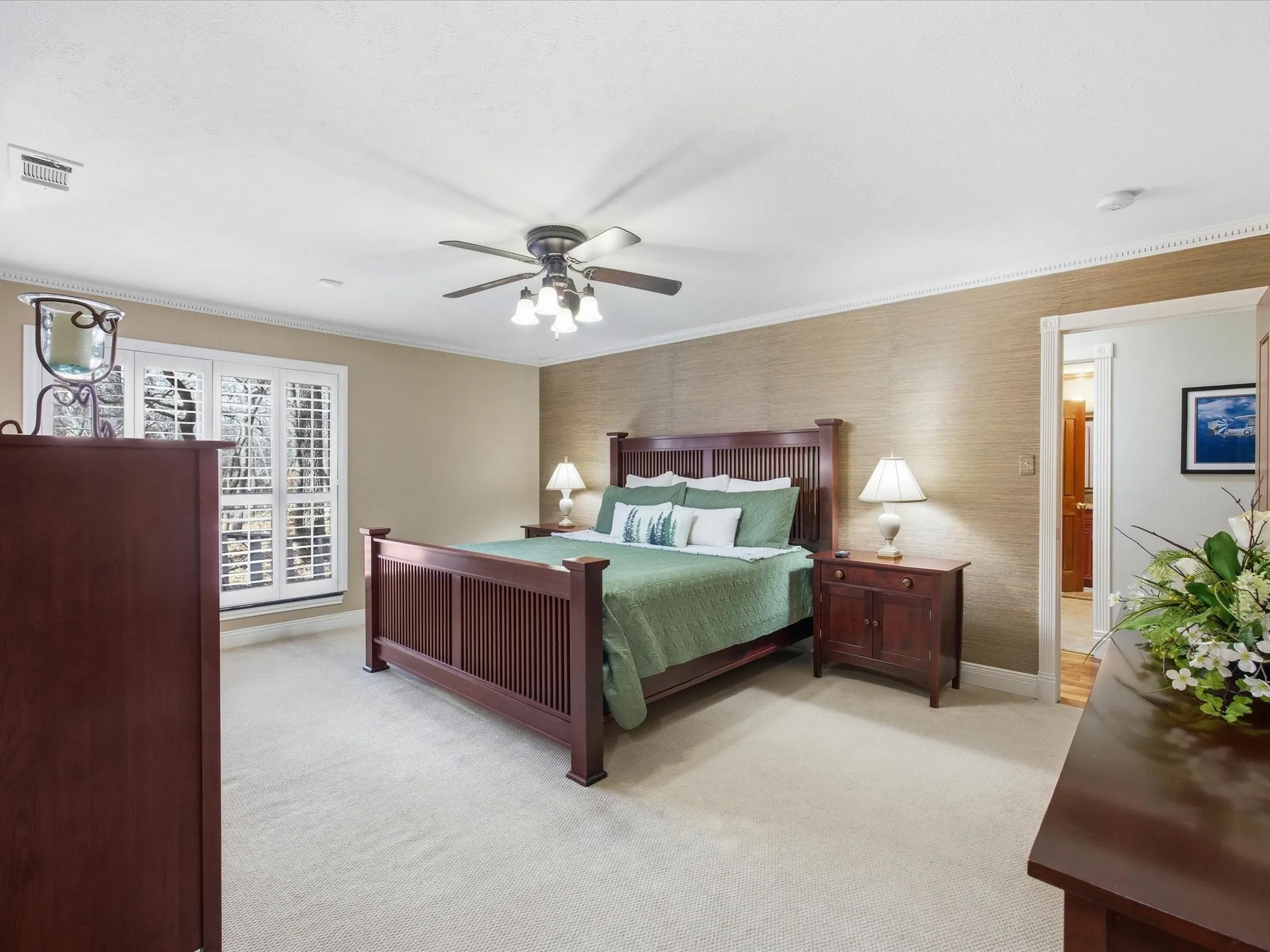 Downstairs Primary Bedroom with light colored carpet, a ceiling fan, crown molding, and wallpapered walls