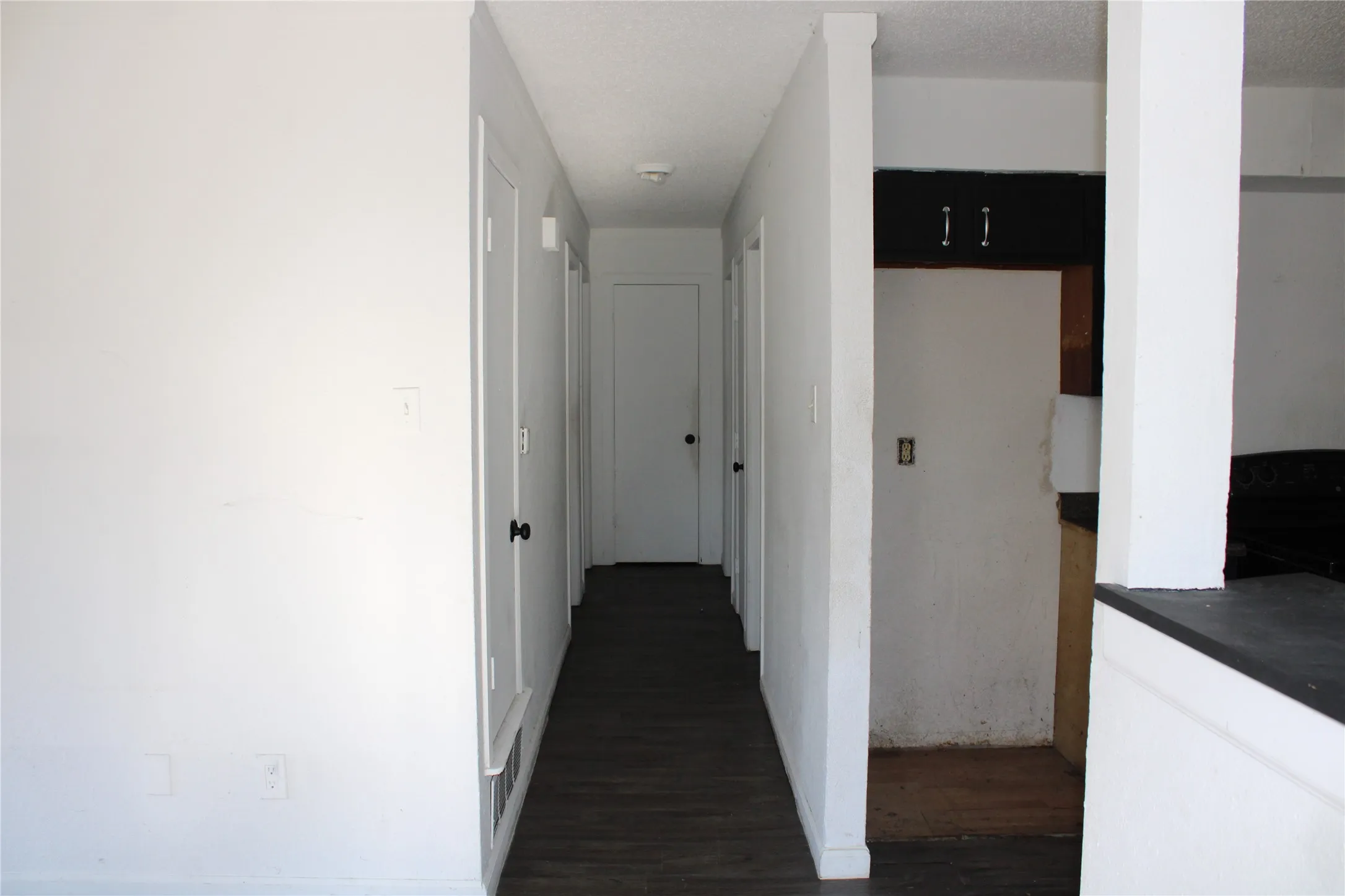 Corridor with dark wood-style flooring and a textured ceiling