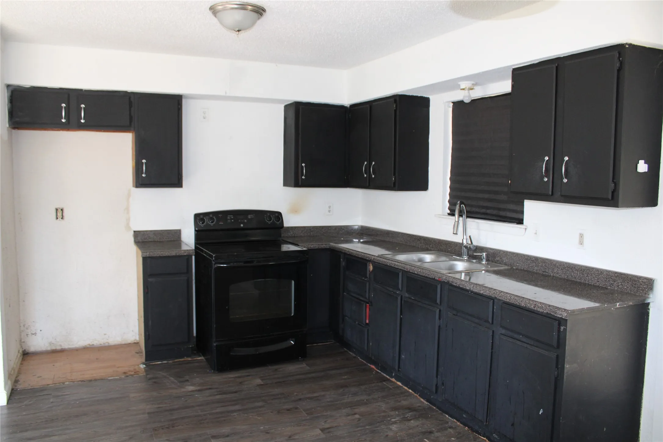 Kitchen with dark cabinetry, dark countertops, black electric range, dark wood-style flooring, and a textured ceiling