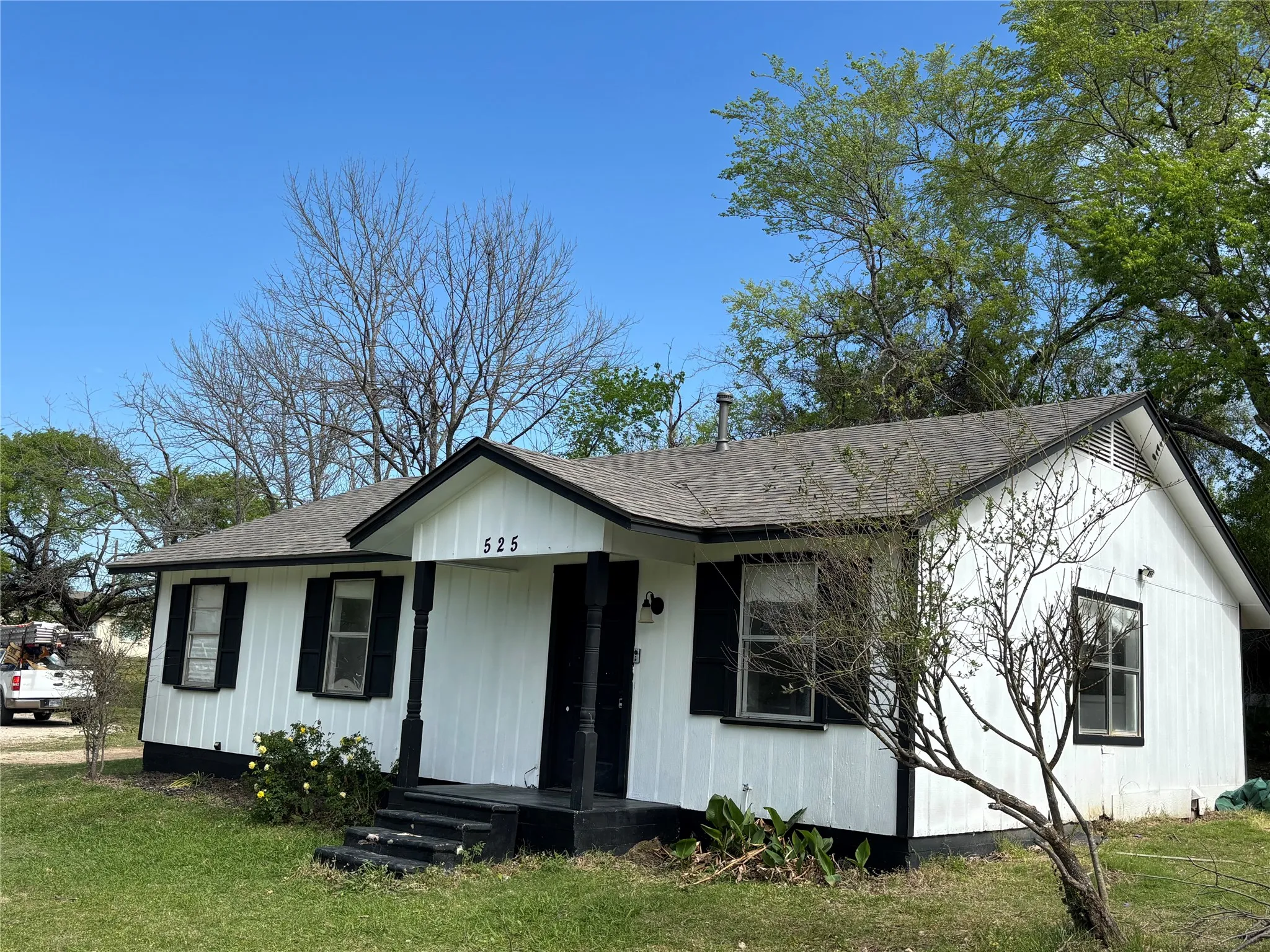 View of front of house featuring a shingled roof and a front lawn