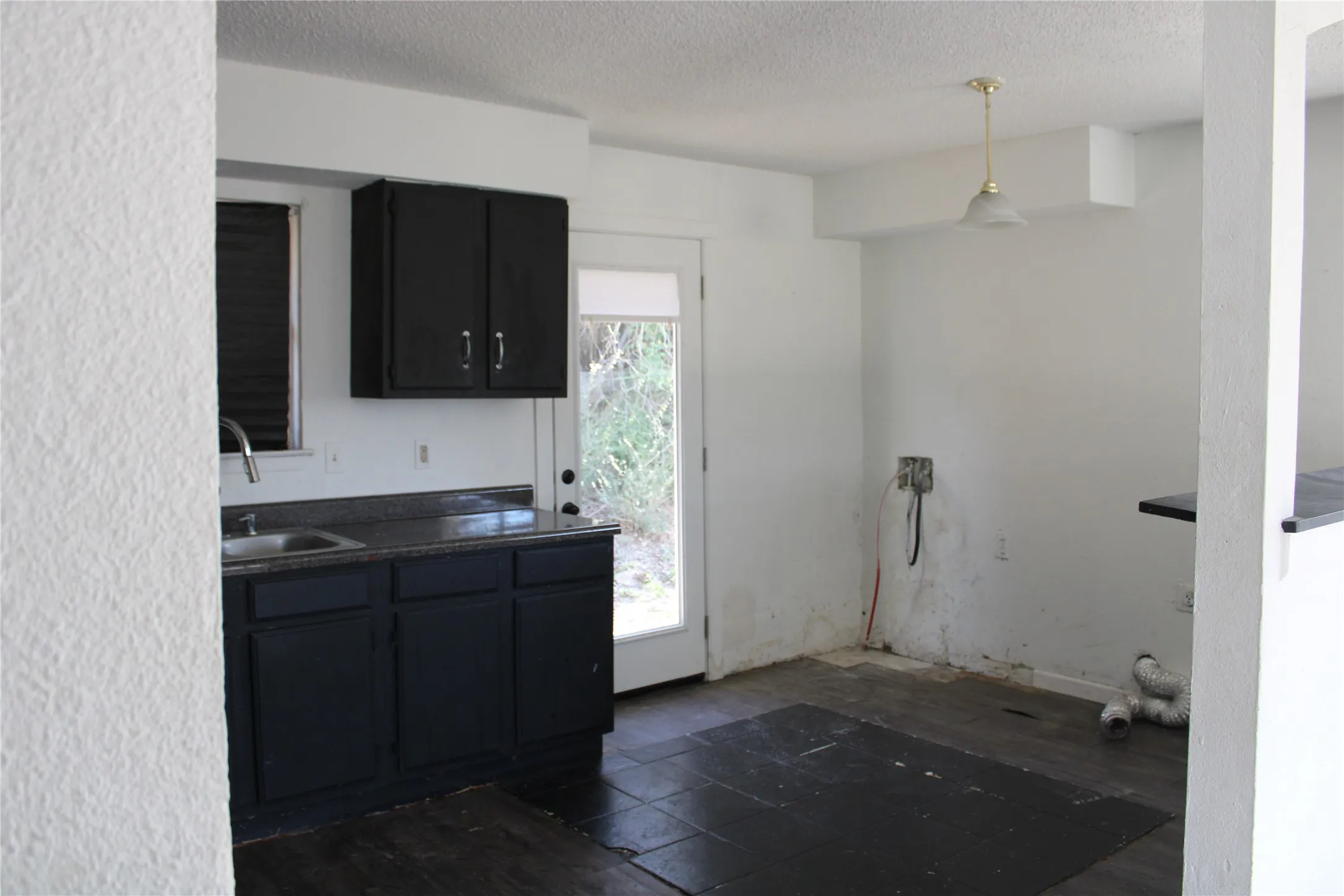 Kitchen with dark countertops, a textured ceiling, decorative light fixtures, and dark cabinetry