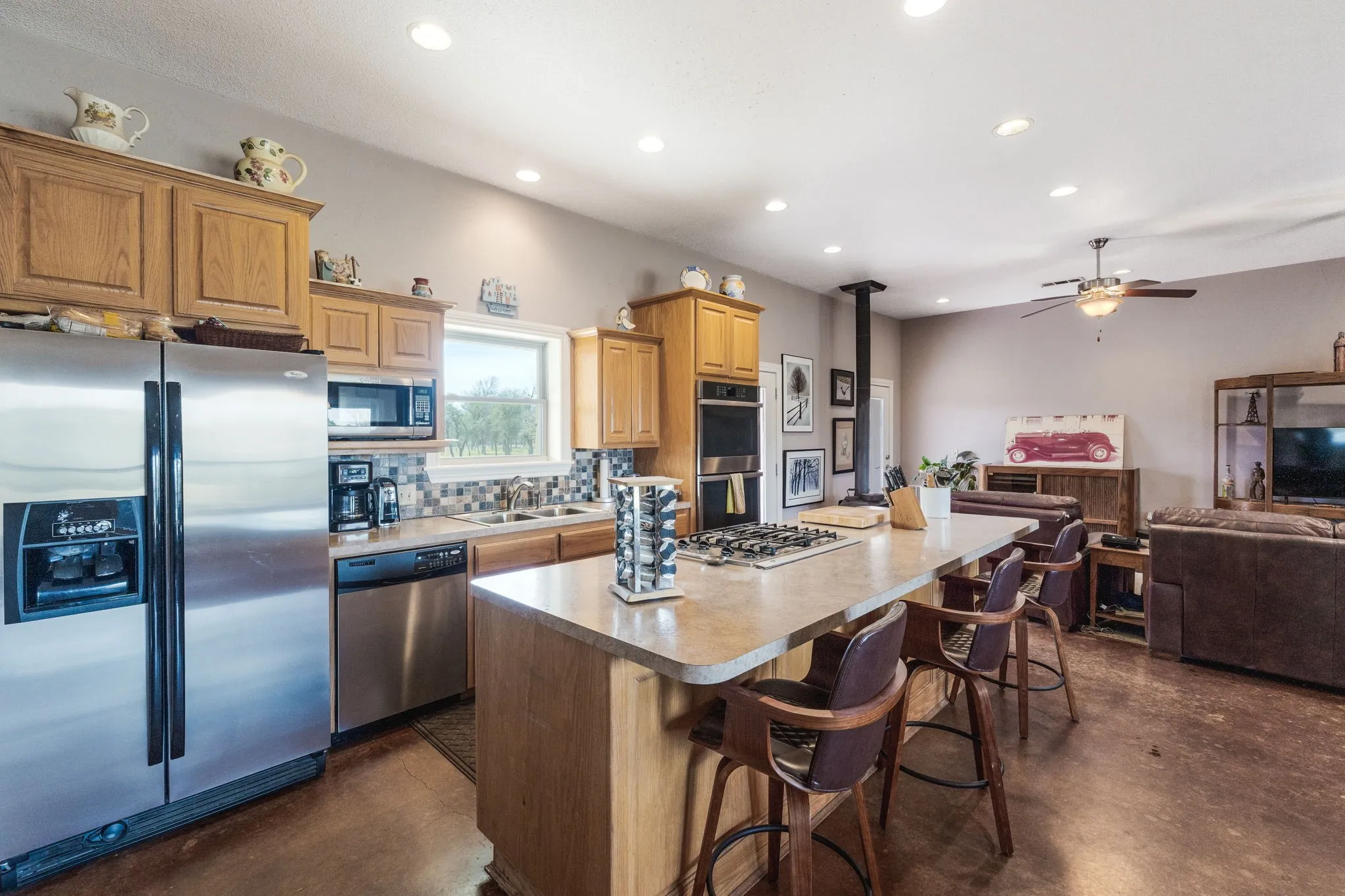 Kitchen featuring stainless steel appliances, finished concrete floors, a center island, a breakfast bar area, and open floor plan
