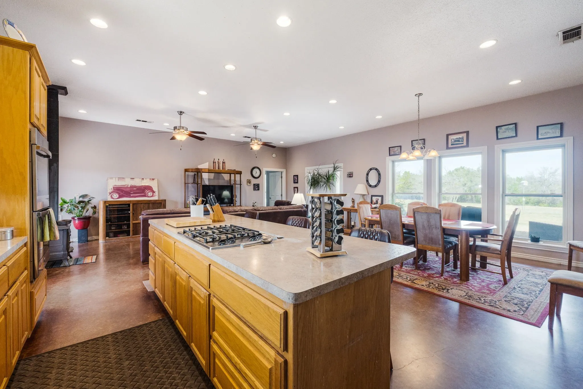 Kitchen with wood finish cabinetry, open floor plan, hanging light fixtures, finished concrete flooring, and light countertops