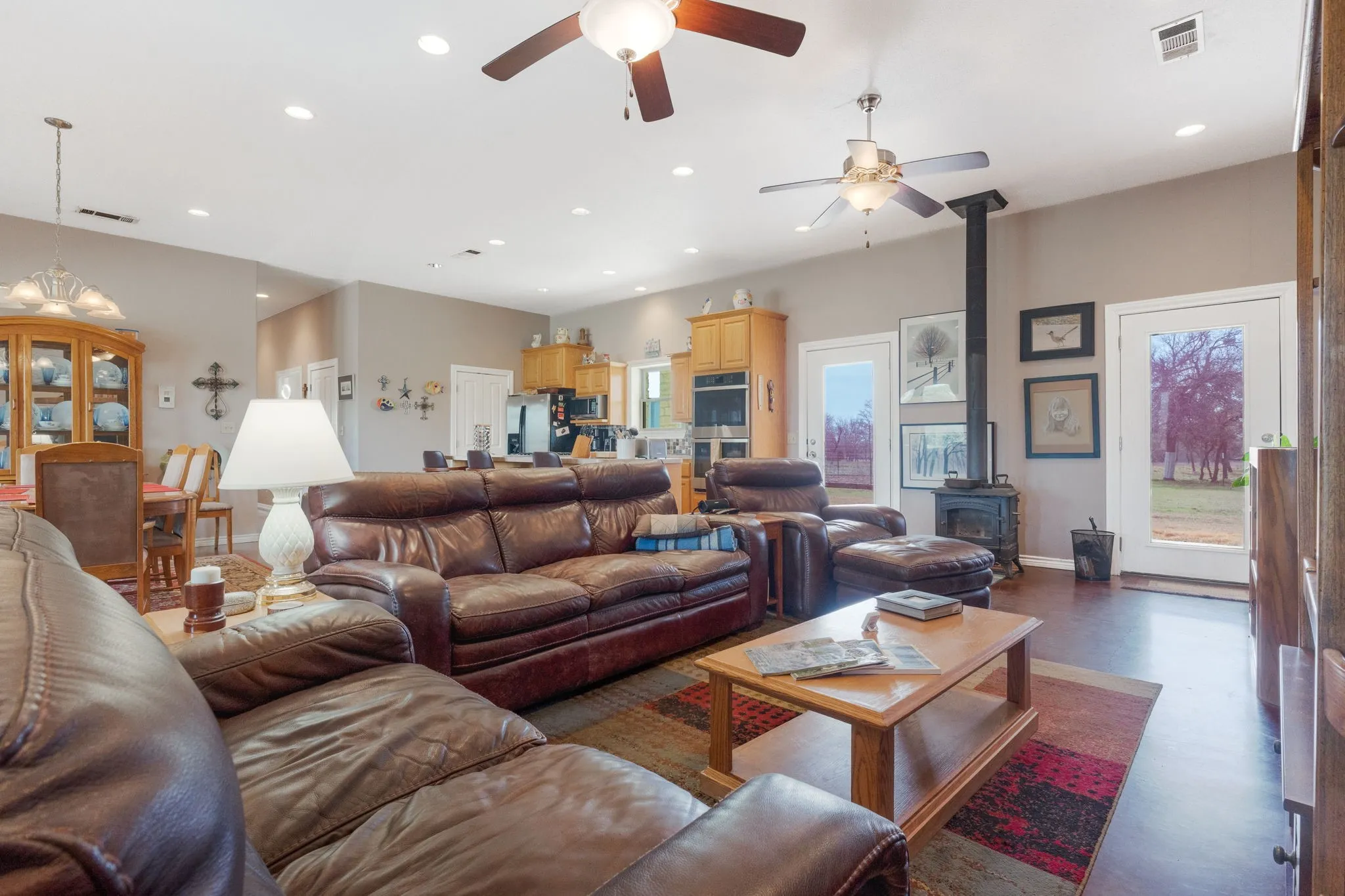 Living room featuring a wood stove, a ceiling fan, finished concrete floors, and a chandelier