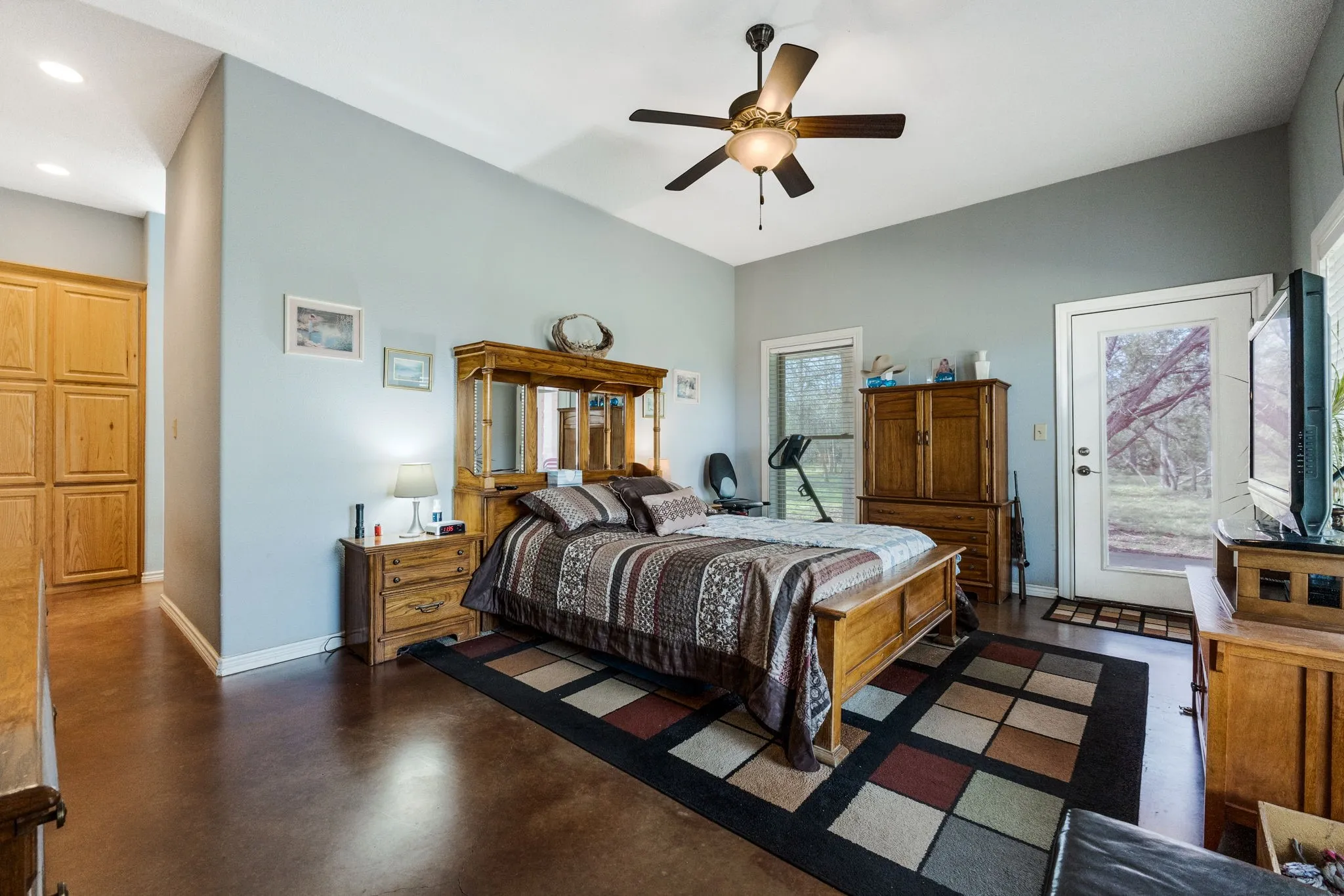 Bedroom with finished concrete flooring, access to exterior, and a ceiling fan