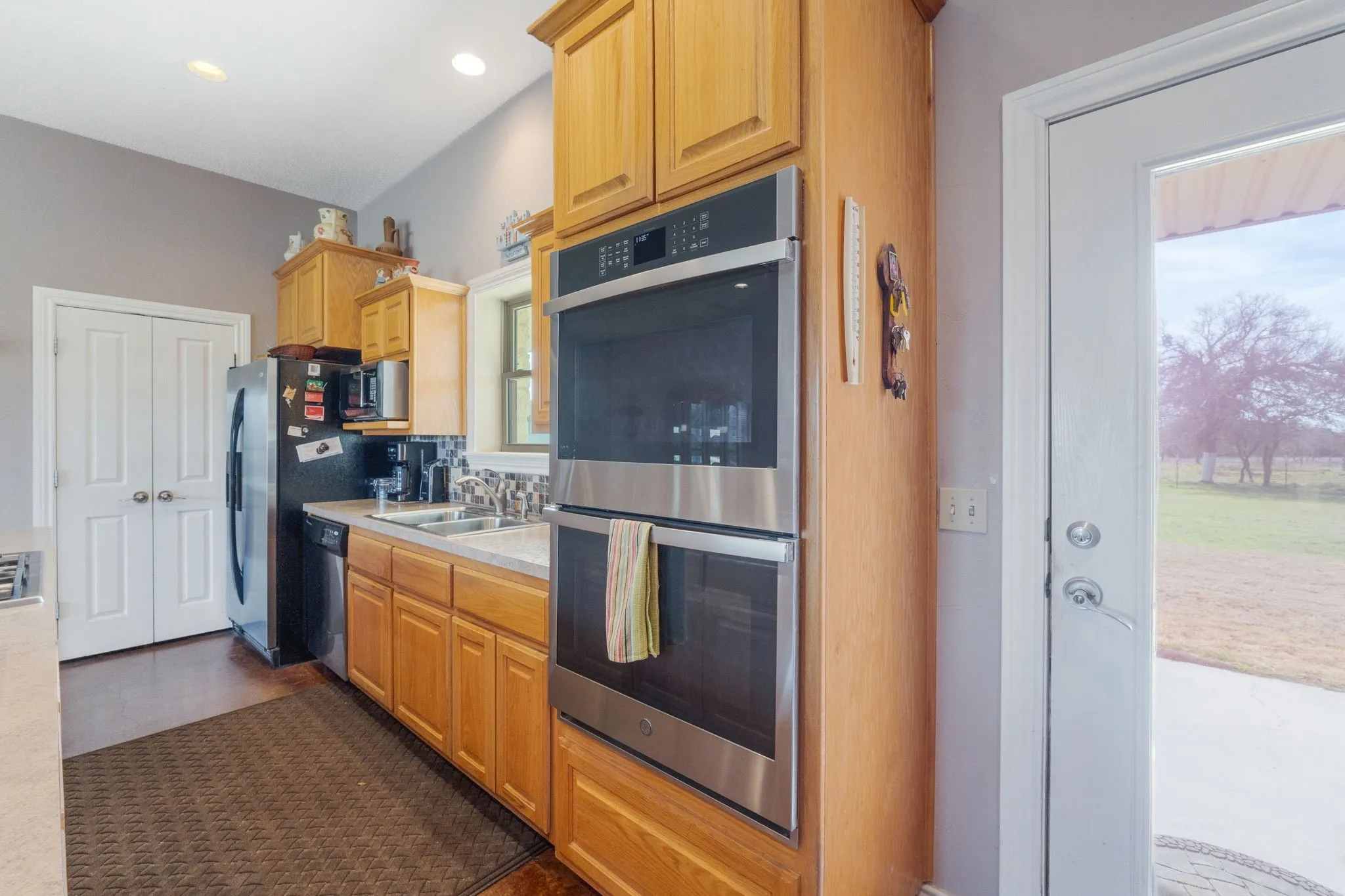 Kitchen with stainless steel appliances, light countertops, backsplash, and dark tile patterned flooring