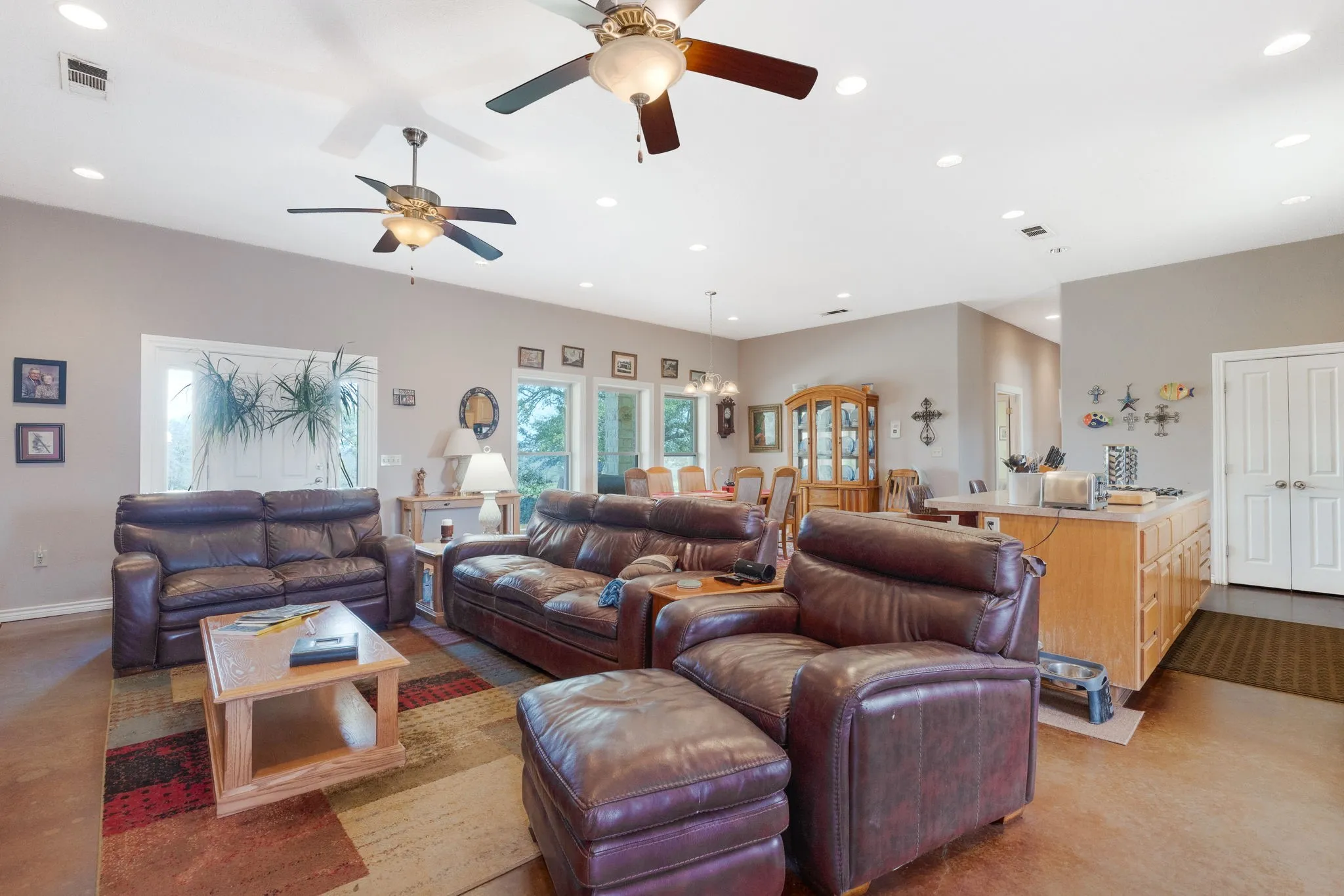 Living area with a ceiling fan, suspended lighting, and concrete floors