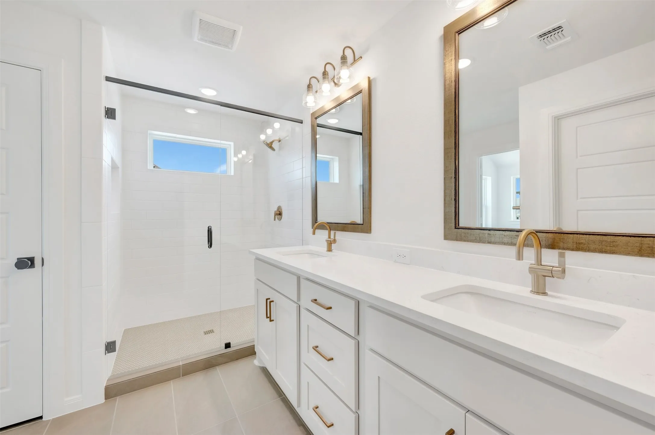Dual vanity with integrated sinks, white cabinetry, and brushed gold fixtures
