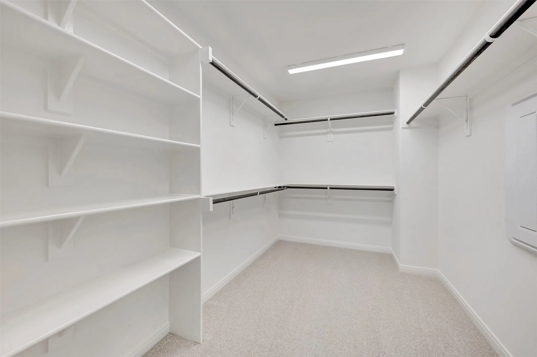 Walk-in closet featuring built-in shelving, multiple hanging rods, light-colored carpeting, and recessed lighting