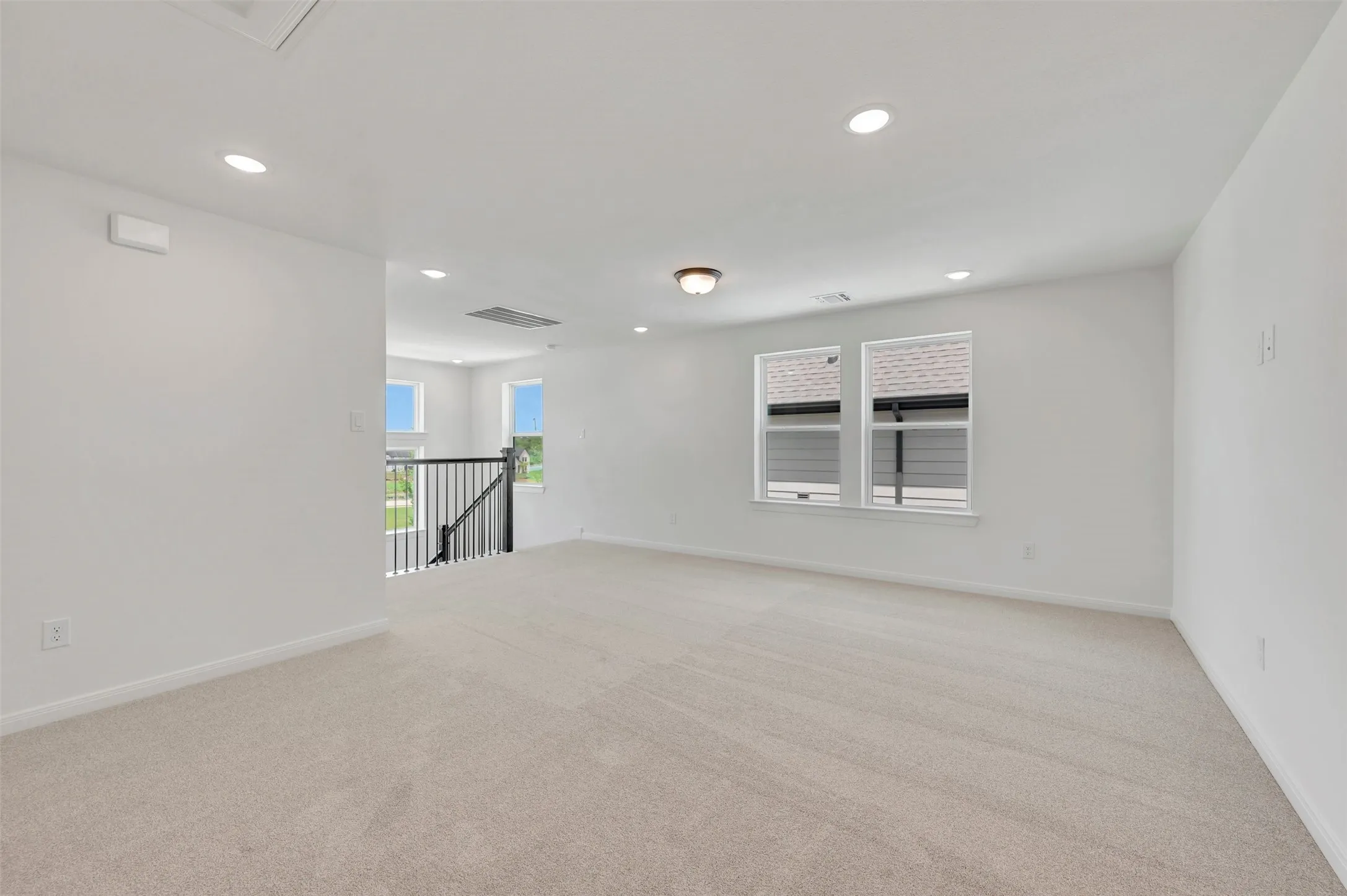 Spacious upper-level room with neutral carpeting and white painted walls