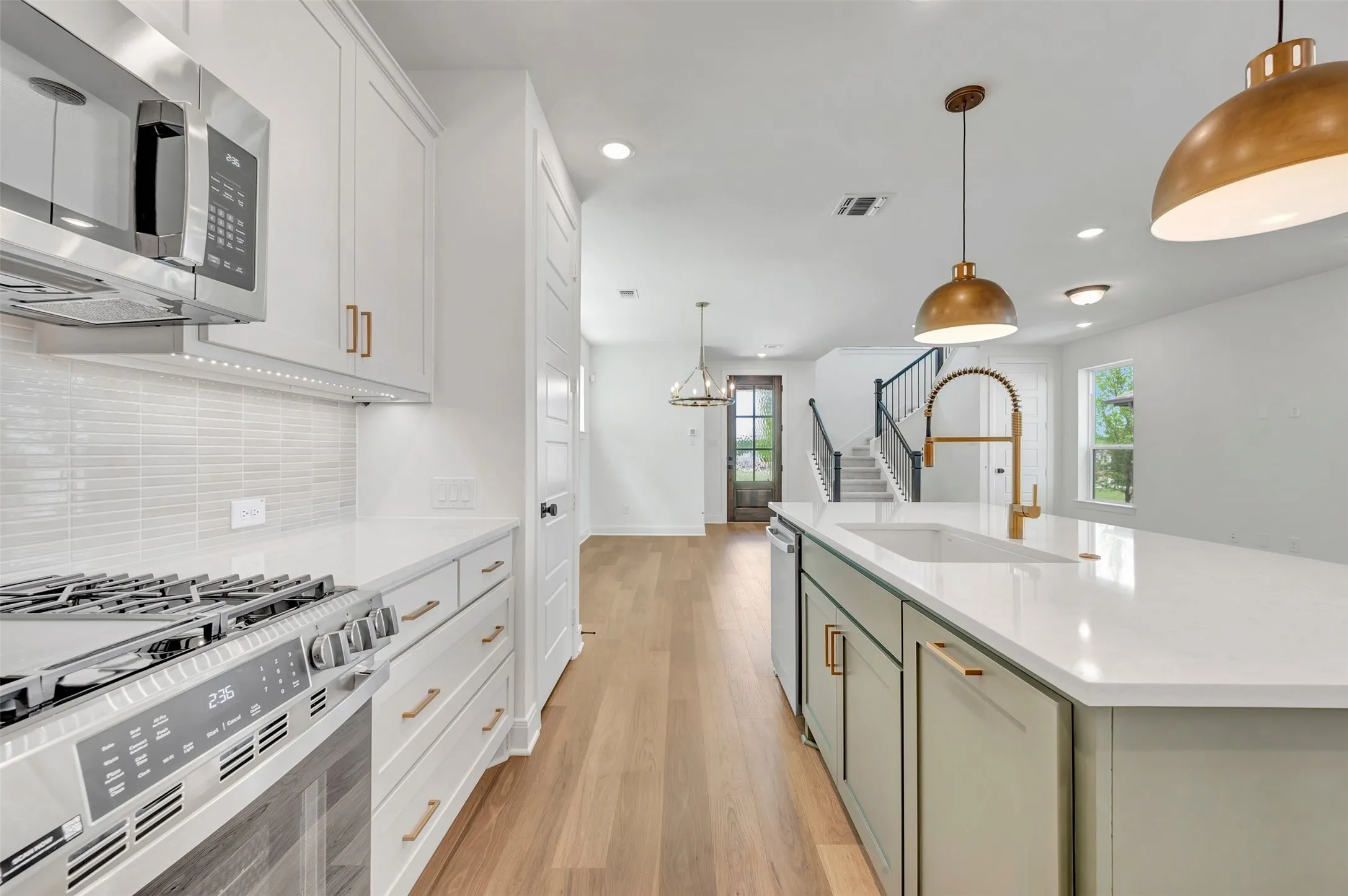 Contemporary kitchen featuring a white subway tile backsplash, stainless steel gas range, and white cabinetry with gold-tone hardware