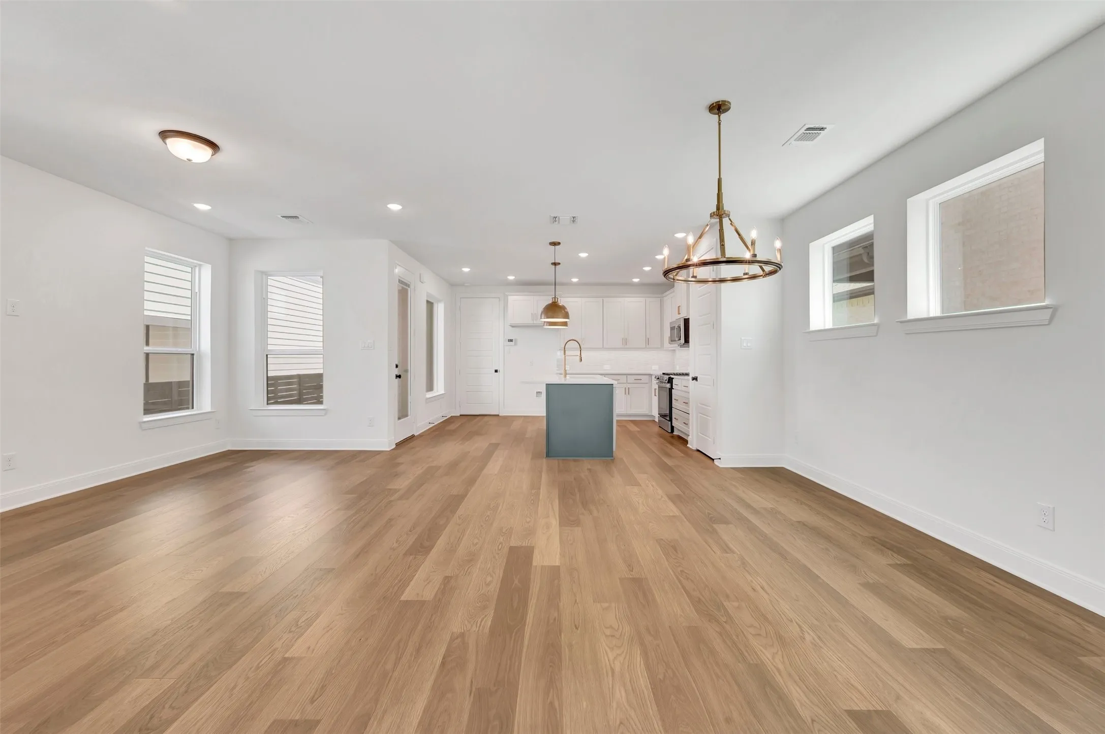 Open-concept living space featuring wood-finish flooring, white walls, and recessed lighting