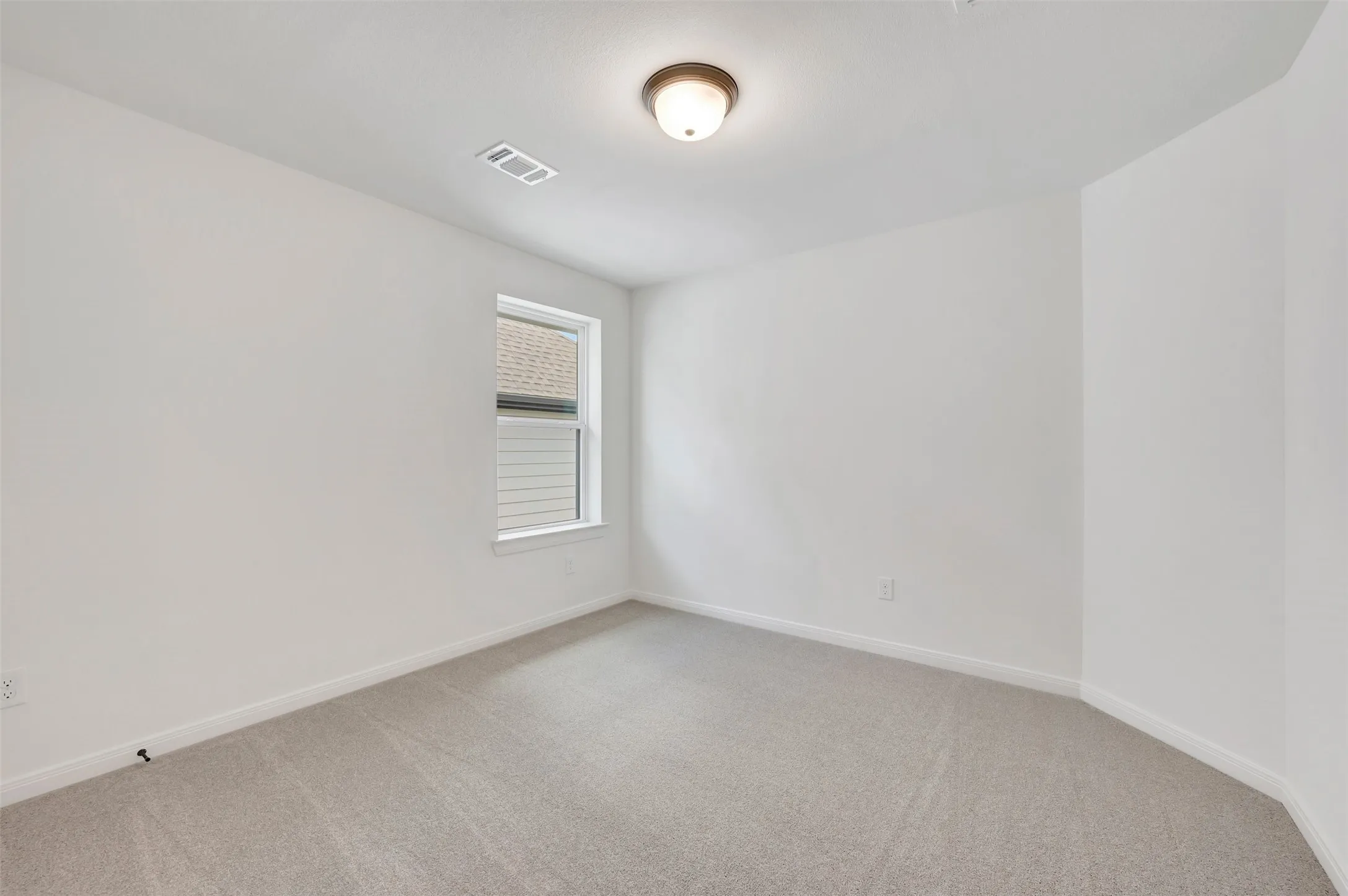 Bright room featuring light gray carpeting, white walls, and a single window