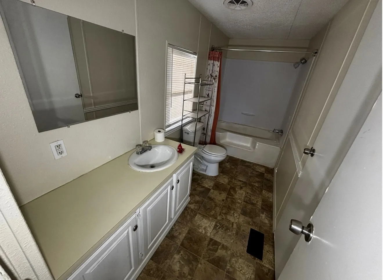 Full bath with vanity, a textured ceiling, stone finish floors, and shower / tub combo
