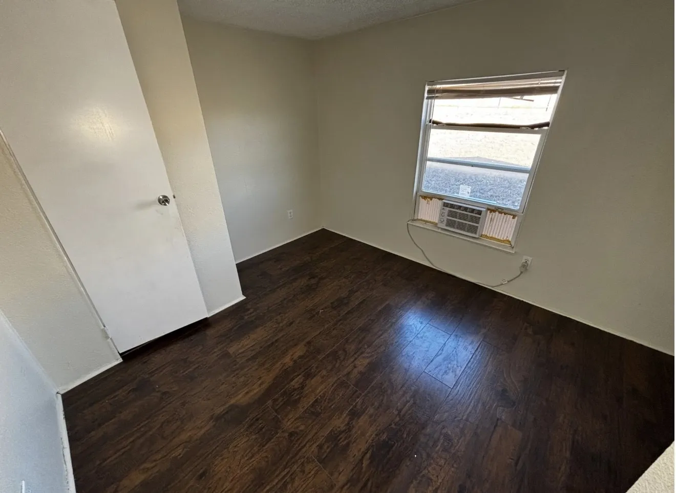 Unfurnished room with dark wood finished floors, a textured ceiling, and cooling unit