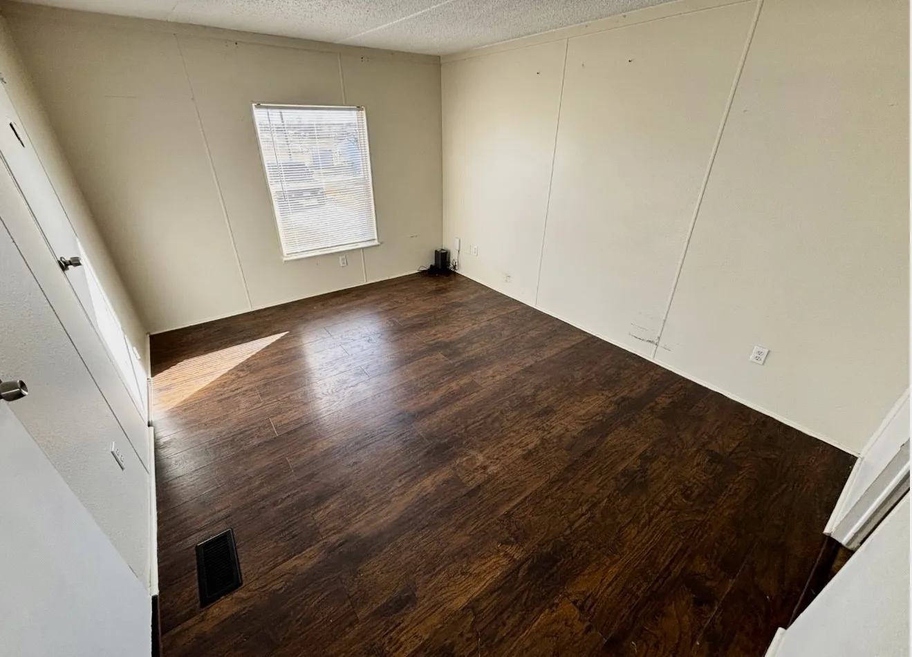Unfurnished bedroom with a decorative wall and wood finished floors