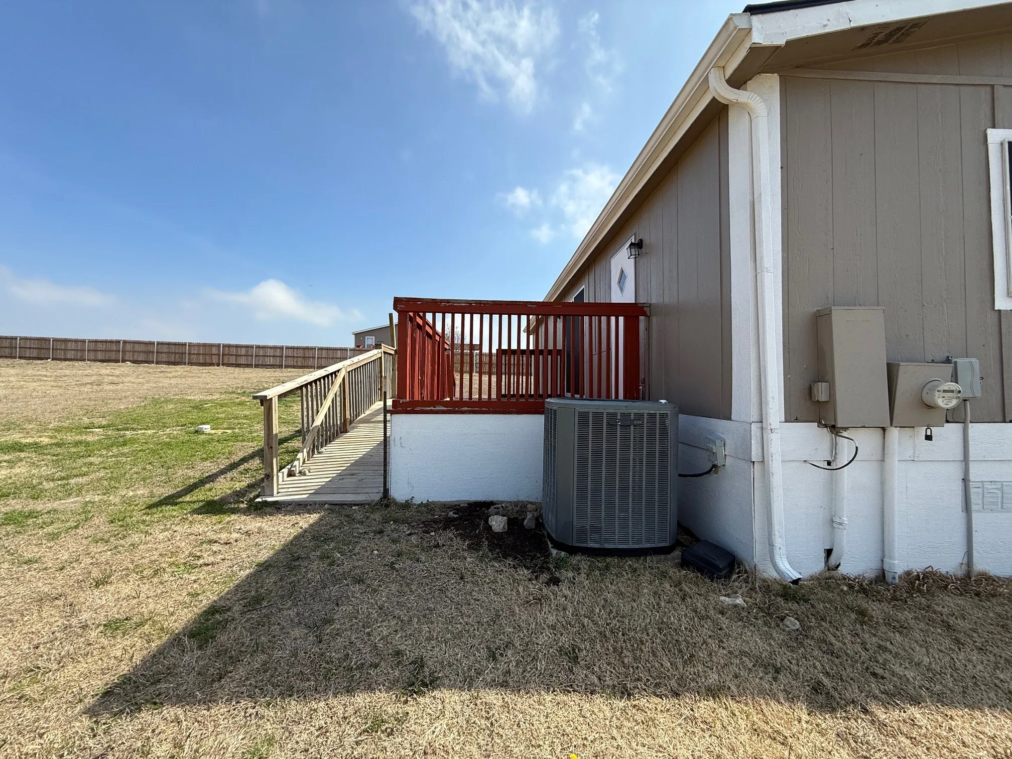 View of side of home with a wooden deck and a central AC unit