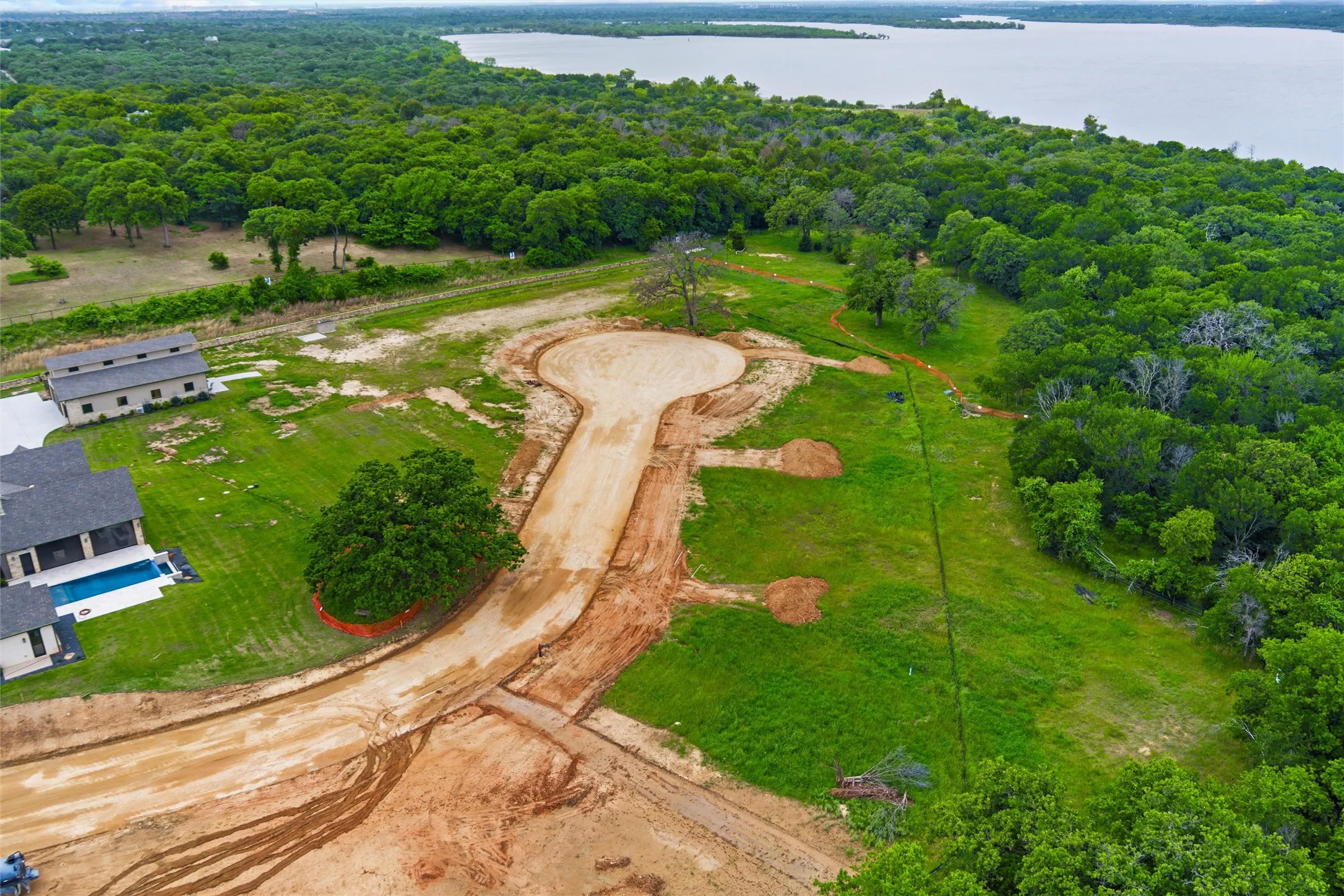 Developing cul-de-sac lot featuring partial clearing, surrounding mature trees, and a distant water body