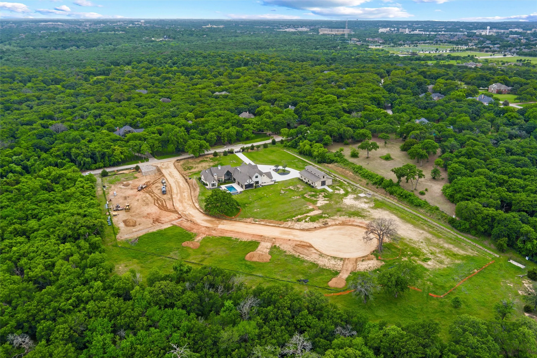 Expansive wooded acreage featuring a large single-family residence, detached auxiliary building, private swimming pool, and a partially developed cul-de-sac with an additional build site