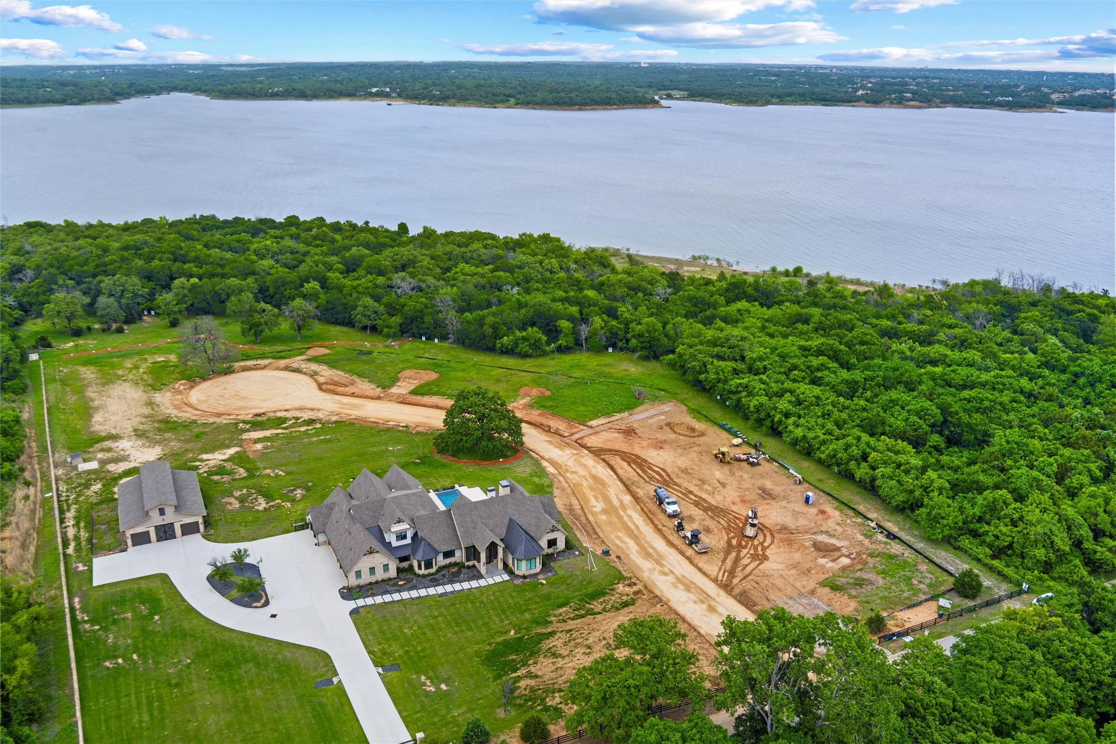Expansive property featuring a waterfront setting, mature trees, substantial land area, a large main residence with a pool, and a detached three-car garage