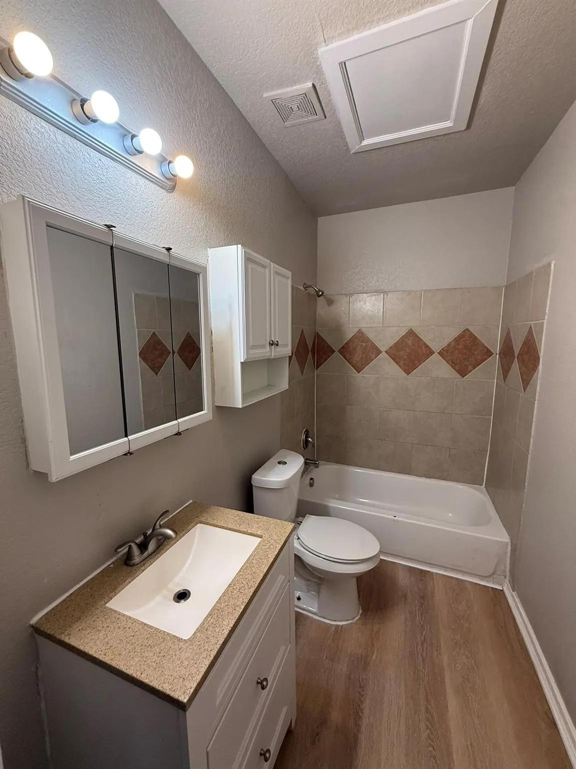 Full bathroom featuring vanity, a textured ceiling, shower / washtub combination, dark wood-style floors, and a textured wall