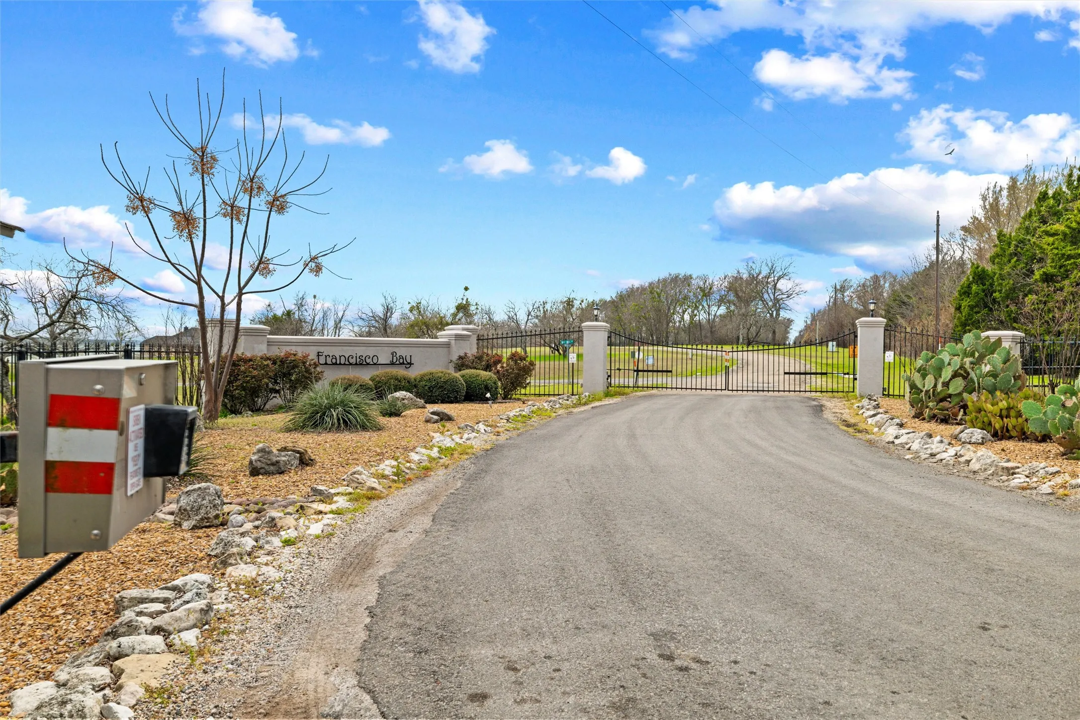 View of asphalt street featuring a gate and a gated entry