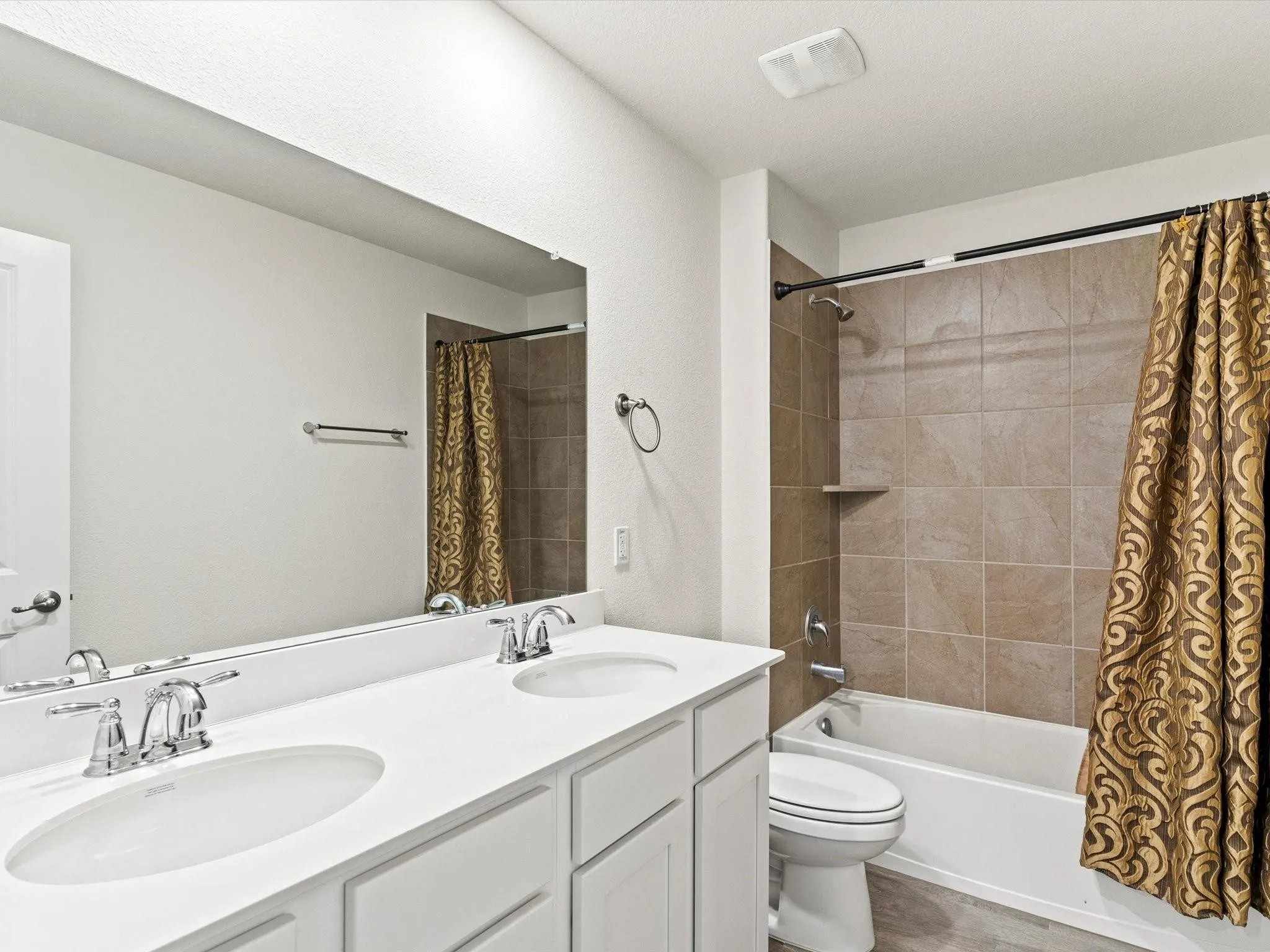 Bathroom featuring a dual vanity with white cabinetry, chrome fixtures, and a large mirror