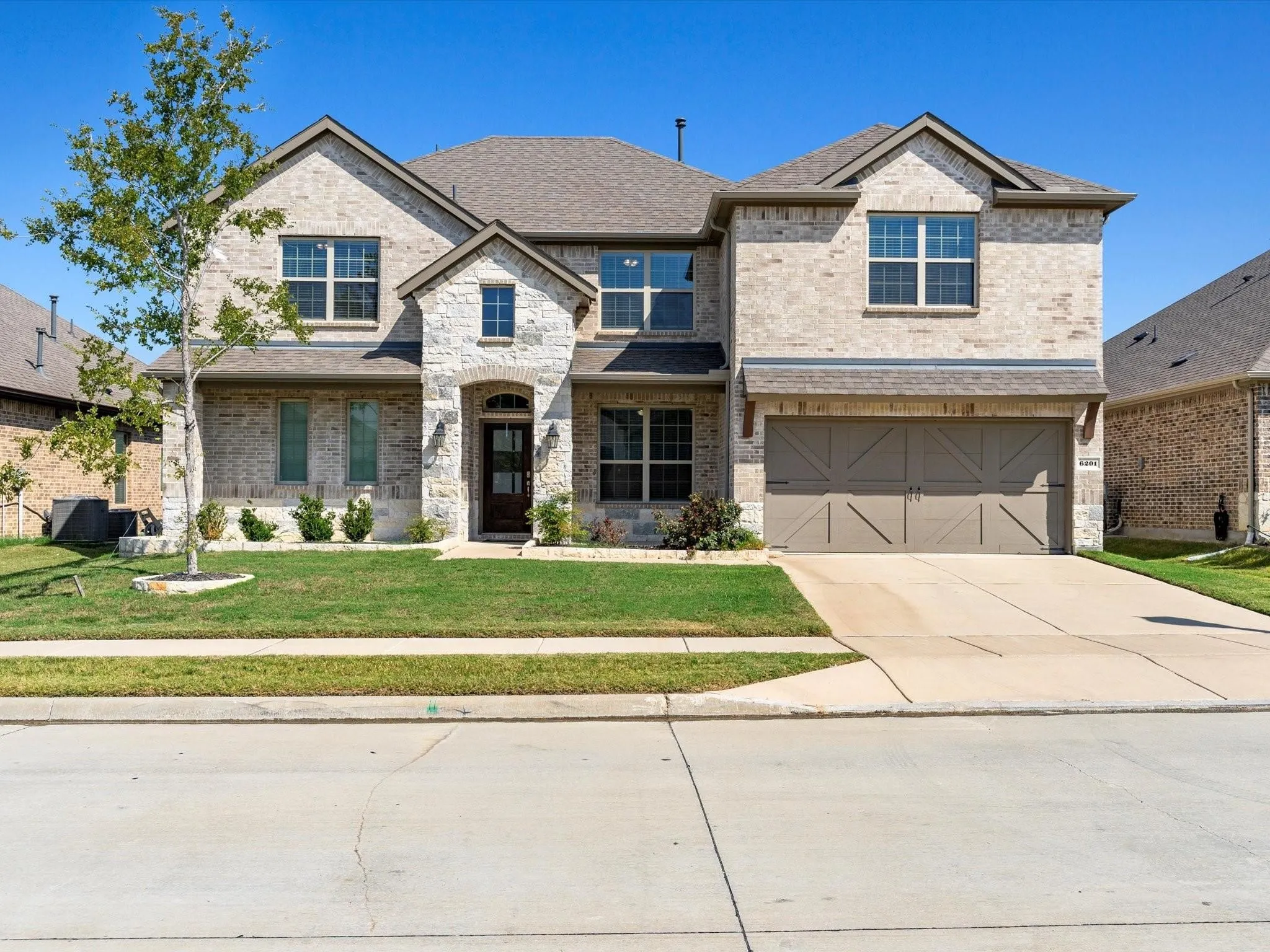 Two-story residence featuring a combination of light-toned brick and natural stone veneer