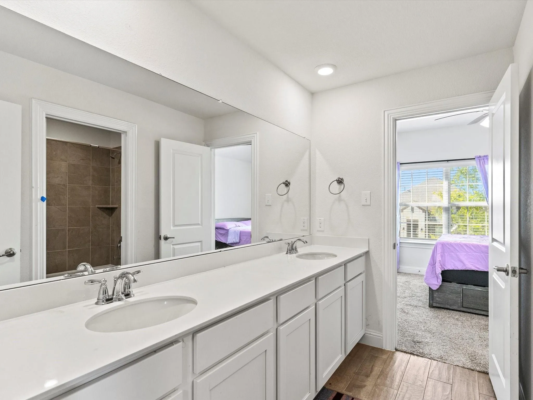 Bathroom featuring a dual vanity with white cabinetry and a light-toned countertop, complete with two undermount sinks and chrome faucets