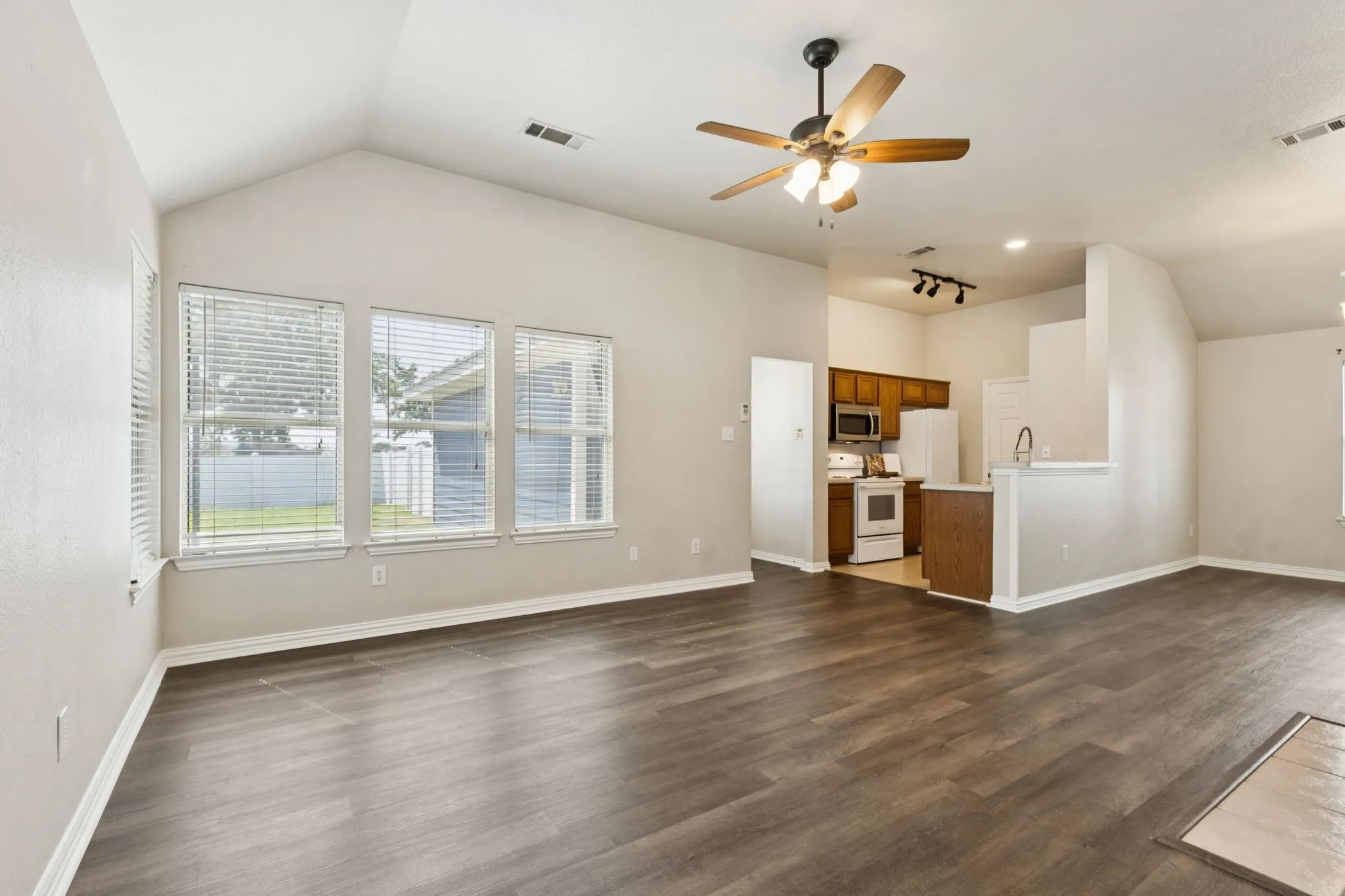 Living room with lofted ceiling, ceiling fan, and dark wood-type flooring