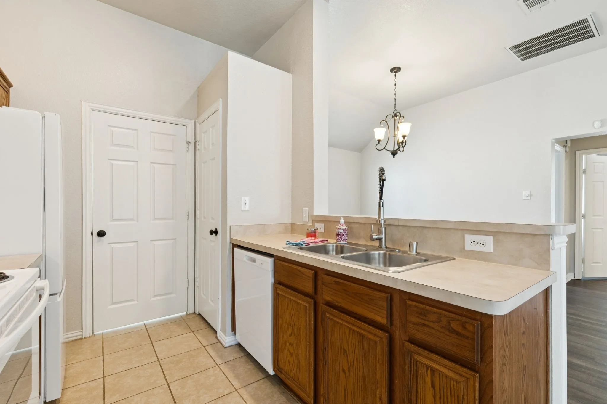 Kitchen with a peninsula, wood finish cabinets, updated white appliances.
