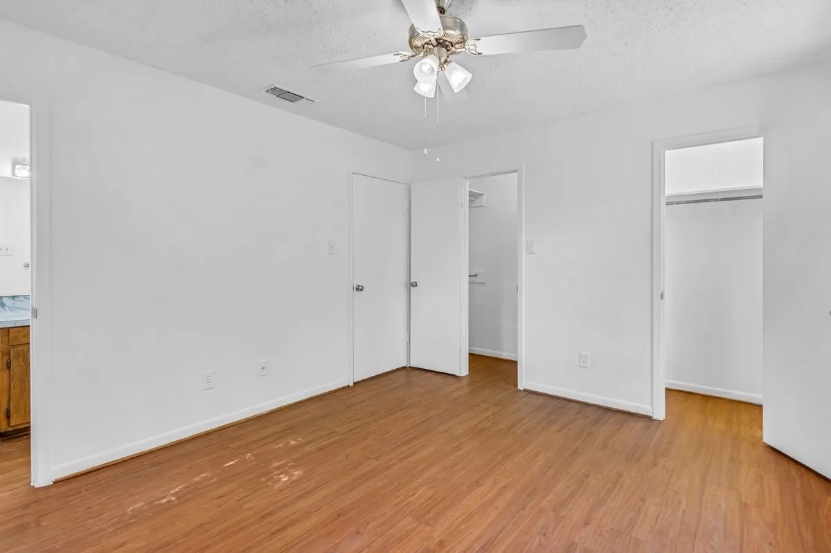 Primary suite featuring two closets, your private ensuite, light wood finished floors, a ceiling fan. Freshely painted