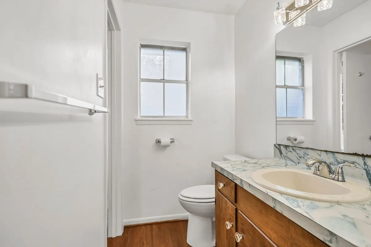 Primary ensuite with full shower, and vanity, dark wood-style flooring, healthy amount of natural light,