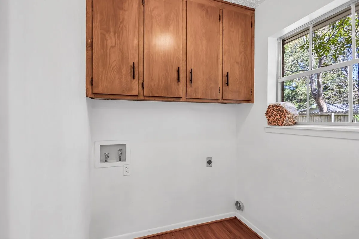 Laundry area featuring dark wood finished floors, hookup for an electric dryer, cabinet space, and washer hookup.