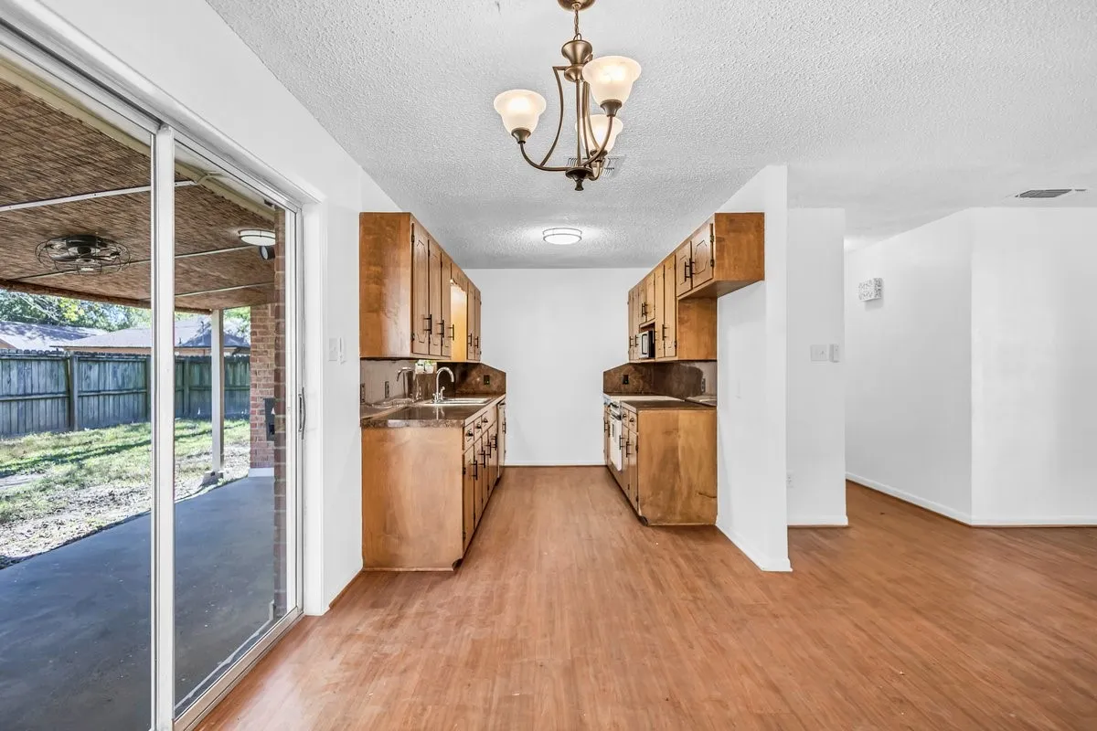 Kitchen featuring wood finish cabinetry, light wood finished floors, hanging lights, and a textured ceiling