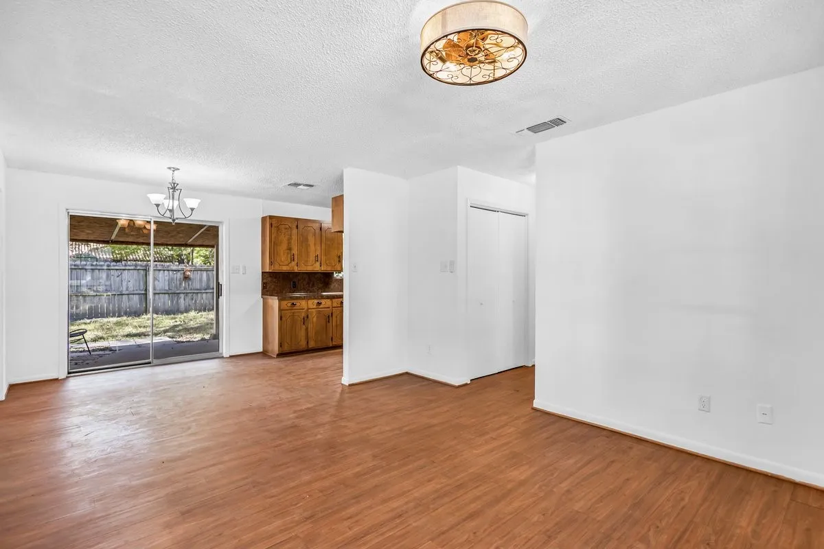  living dining room featuring suspended lighting, a textured ceiling, and wood finished floors