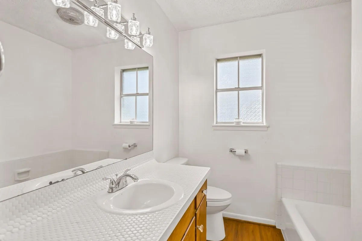 Full bath with plenty of natural light, a bath, vanity, light wood finished floors