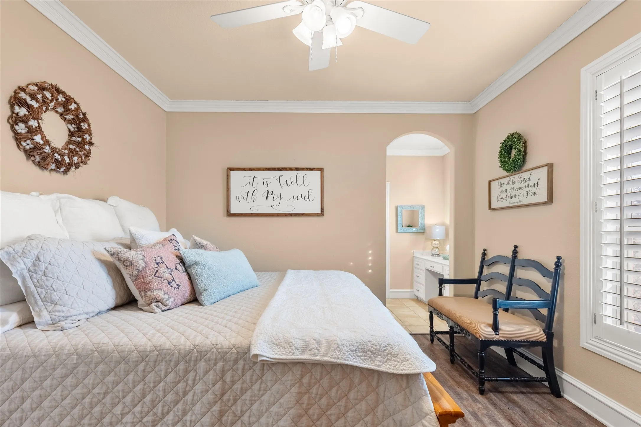 Bedroom with ornamental molding, wood finished floors, a ceiling fan, arched walkways, and multiple windows