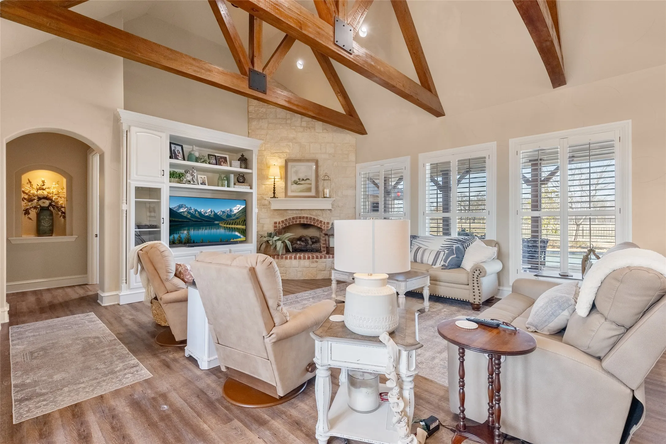 Living room featuring lofted ceiling, a fireplace, arched walkways, wood finished floors, and recessed lighting