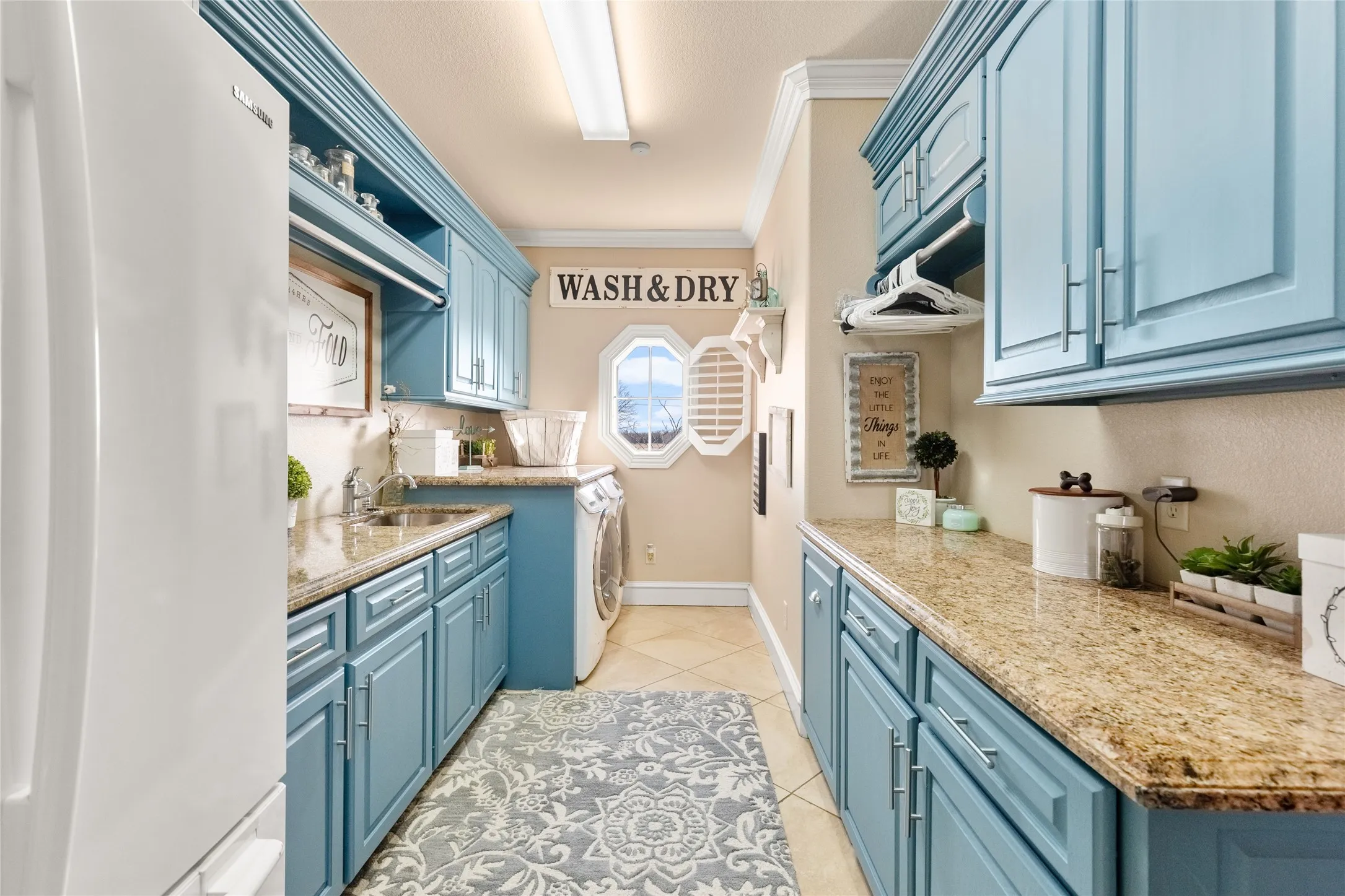 Kitchen featuring blue cabinetry, freestanding refrigerator, ornamental molding, light tile patterned floors, and open shelves