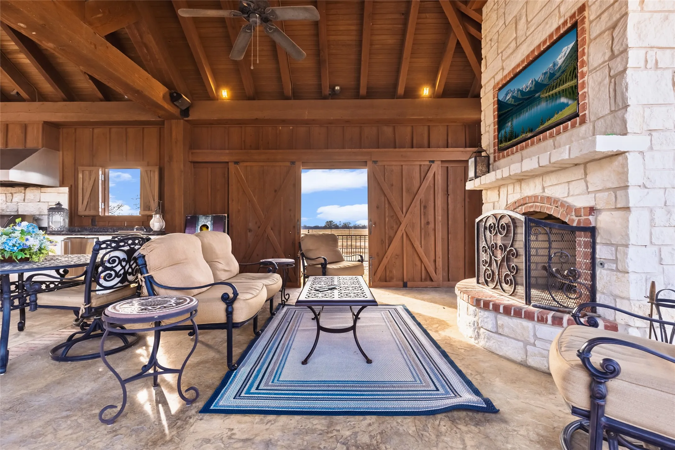 Living room featuring a large fireplace, ceiling fan, a high wood beamed ceiling, and wood walls