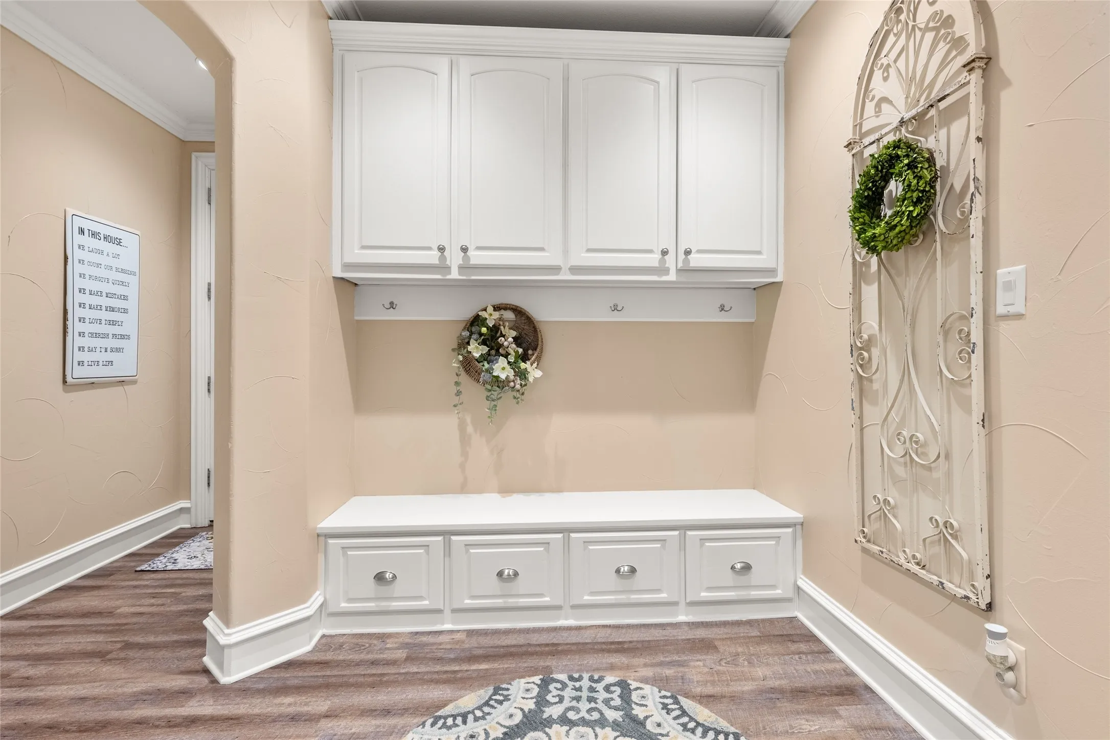 Mudroom featuring ornamental molding, dark wood-style floors, and arched walkways