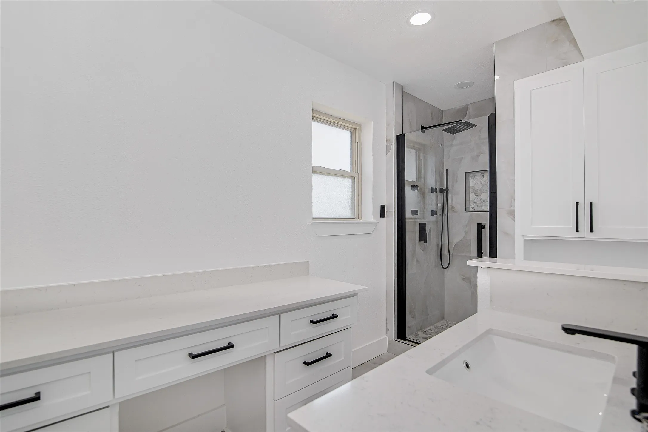 Bathroom featuring vanity, a marble finish shower, and recessed lighting and her vanity.