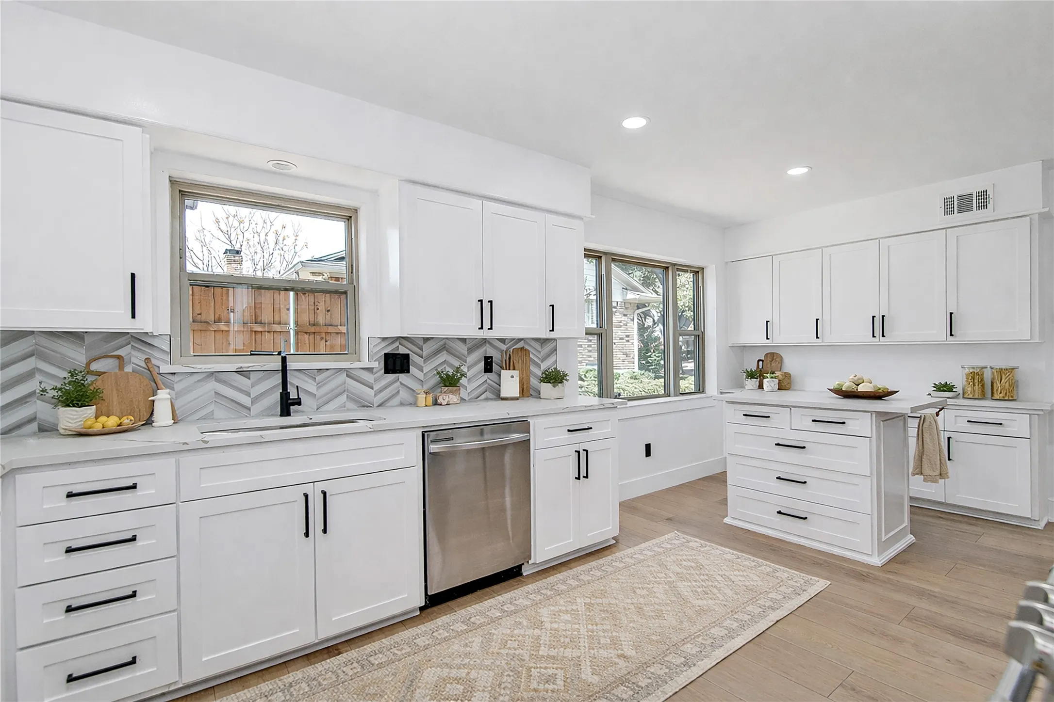 Kitchen featuring white cabinets, stainless steel dishwasher, recessed lighting, decorative backsplash, and light stone counters