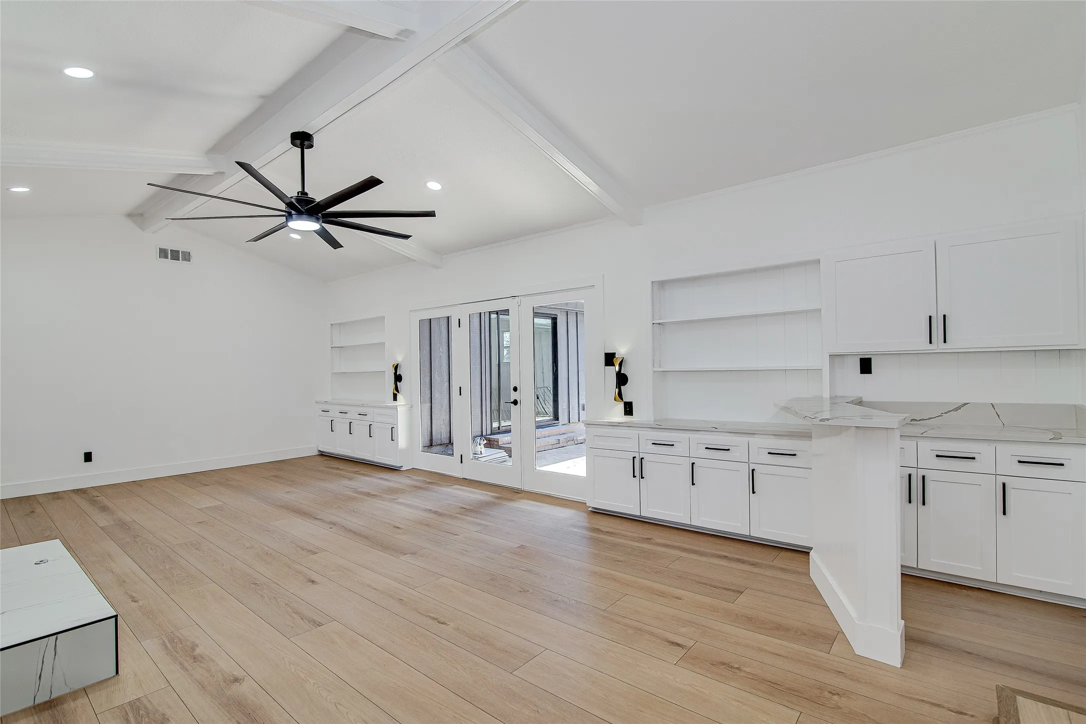 Unfurnished living room featuring light wood finished floors, a ceiling fan, lofted ceiling with beams, built in features, and recessed lighting
