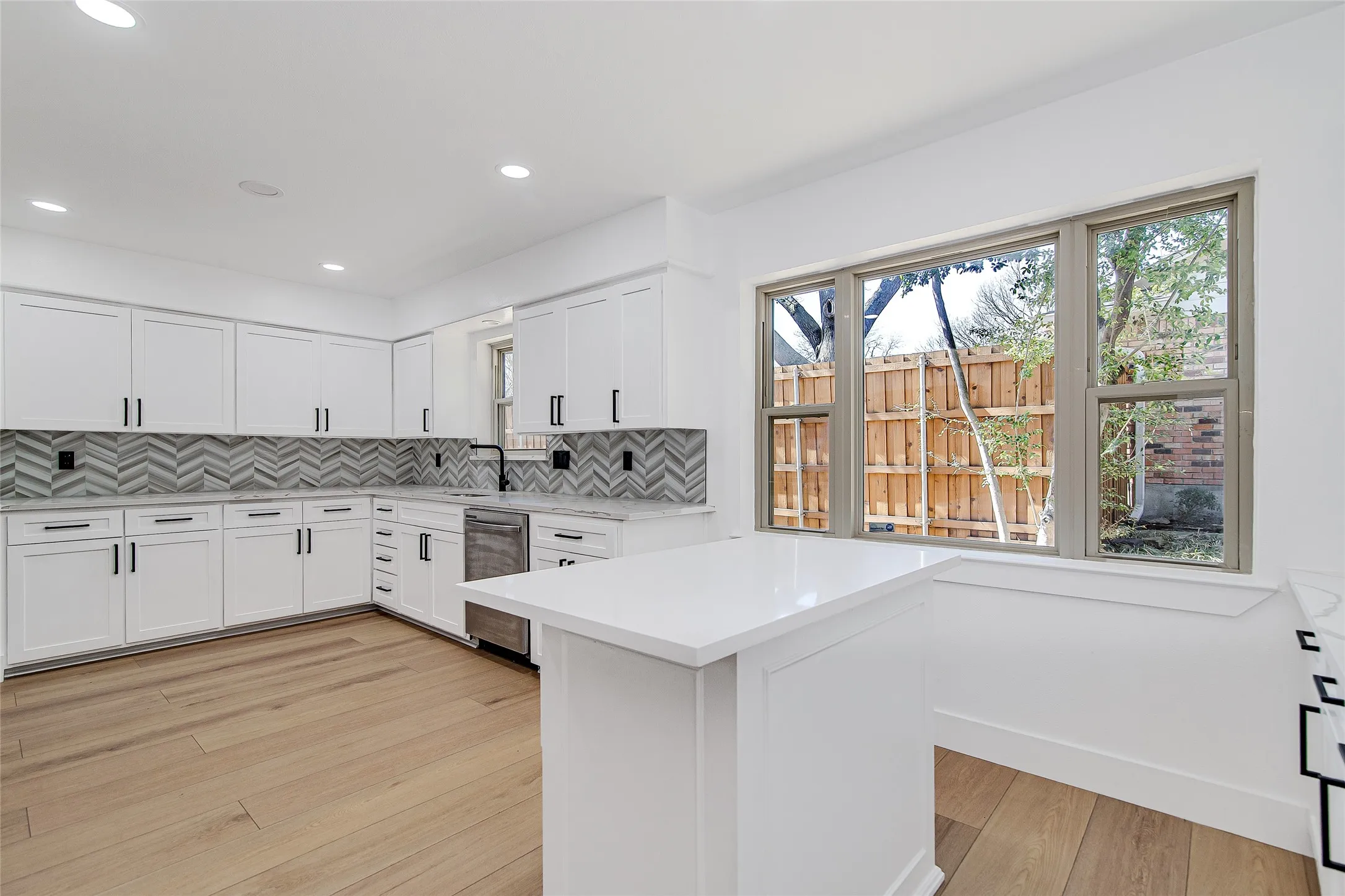 Kitchen featuring decorative backsplash, white cabinets, light wood-type flooring, dishwasher, and recessed lighting